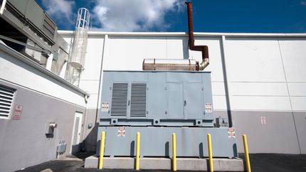 A large generator is sitting outside of a building