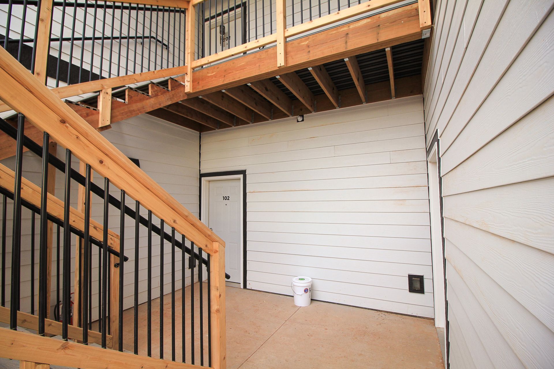 Modern townhouse exterior with wooden decks, stairs, and beige siding