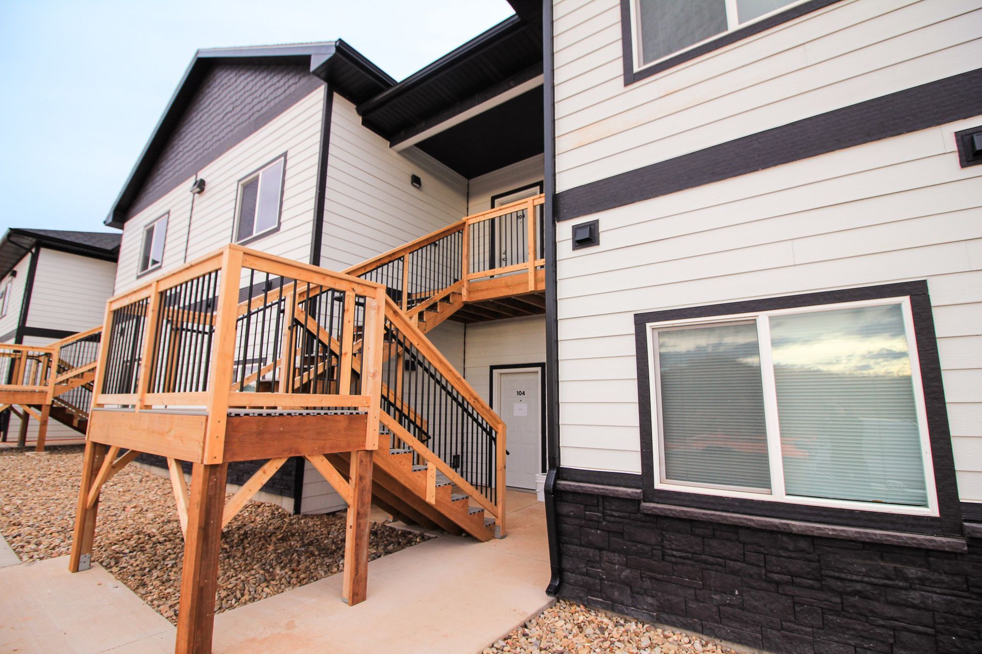 Covered balcony with sliding glass door, white siding, wooden deck, and outdoor air conditioner unit.