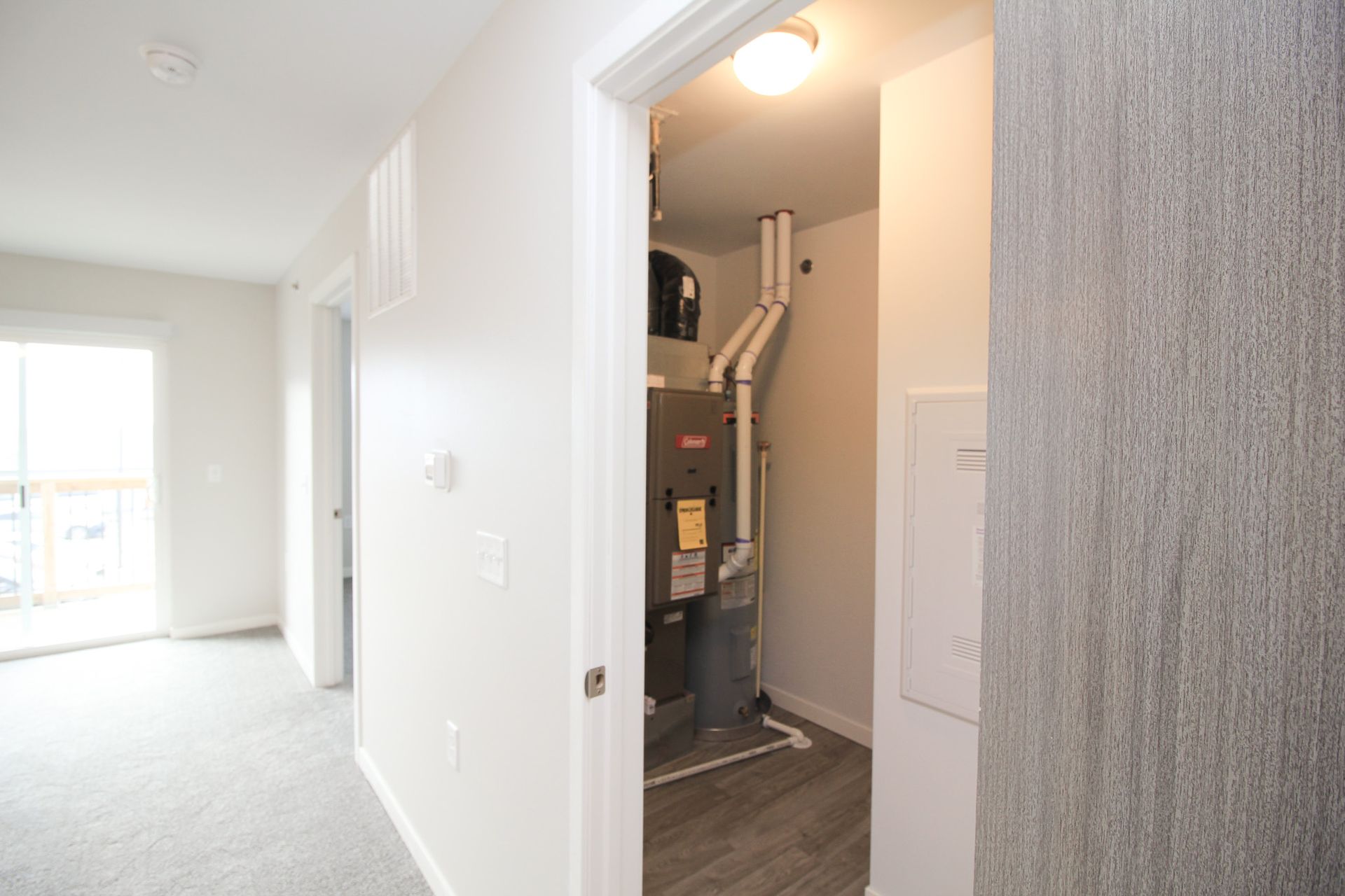 Bright hallway leading to a utility closet with furnace equipment and a lit ceiling light
