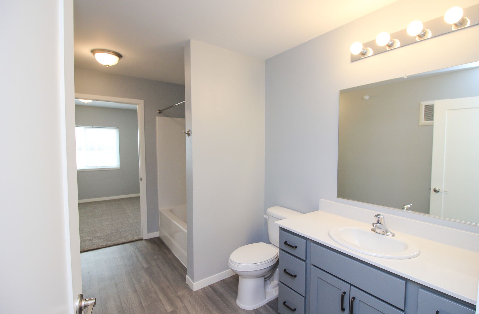 Bright modern bathroom with vanity, mirror lights, toilet, and walk-in shower area