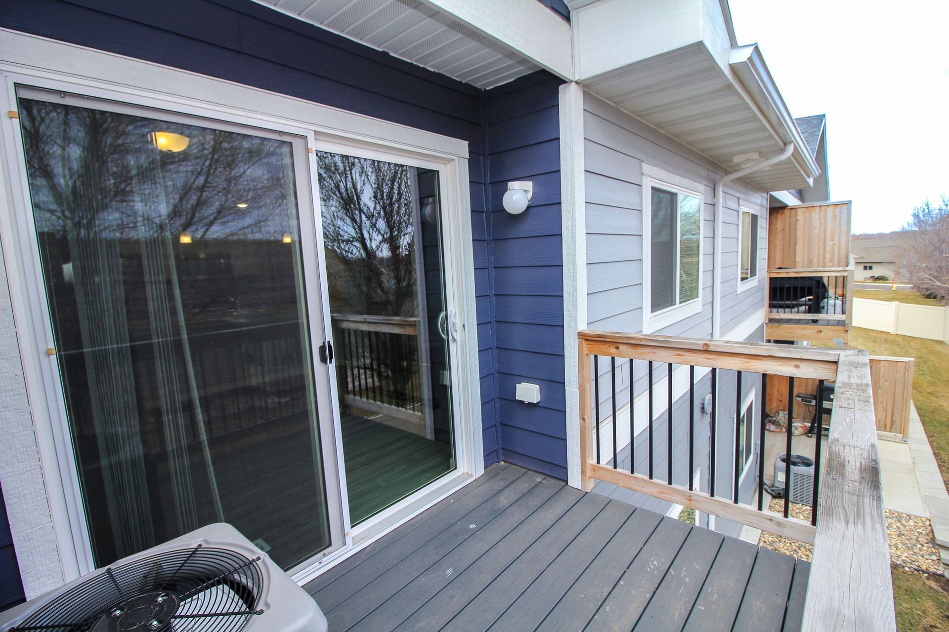 Blue house deck with sliding glass doors, railing, and outdoor seating area