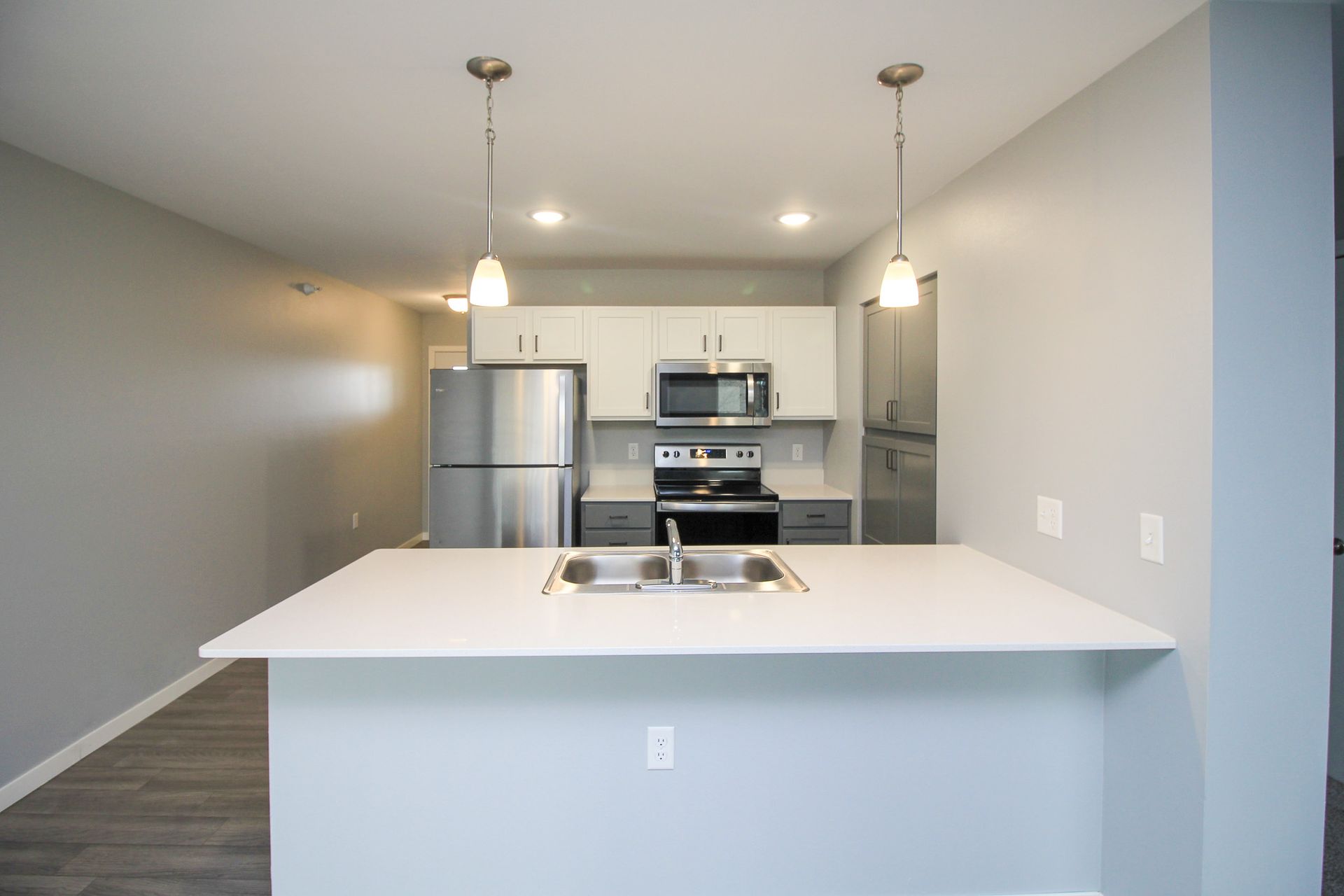 Modern kitchen with white island, stainless steel appliances, and pendant lights