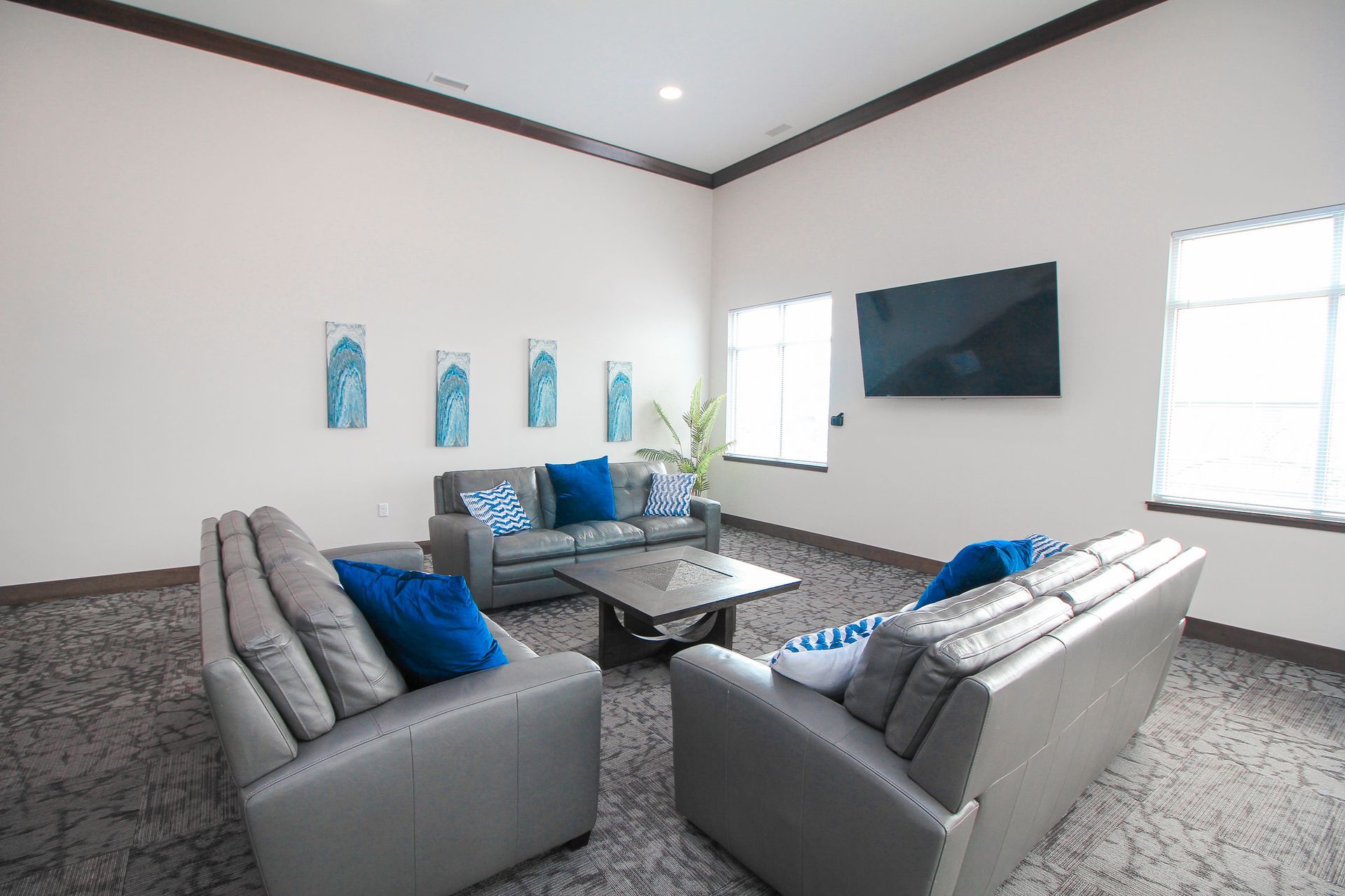Modern living room with gray sofas, blue accents, wall art, and a wall-mounted TV