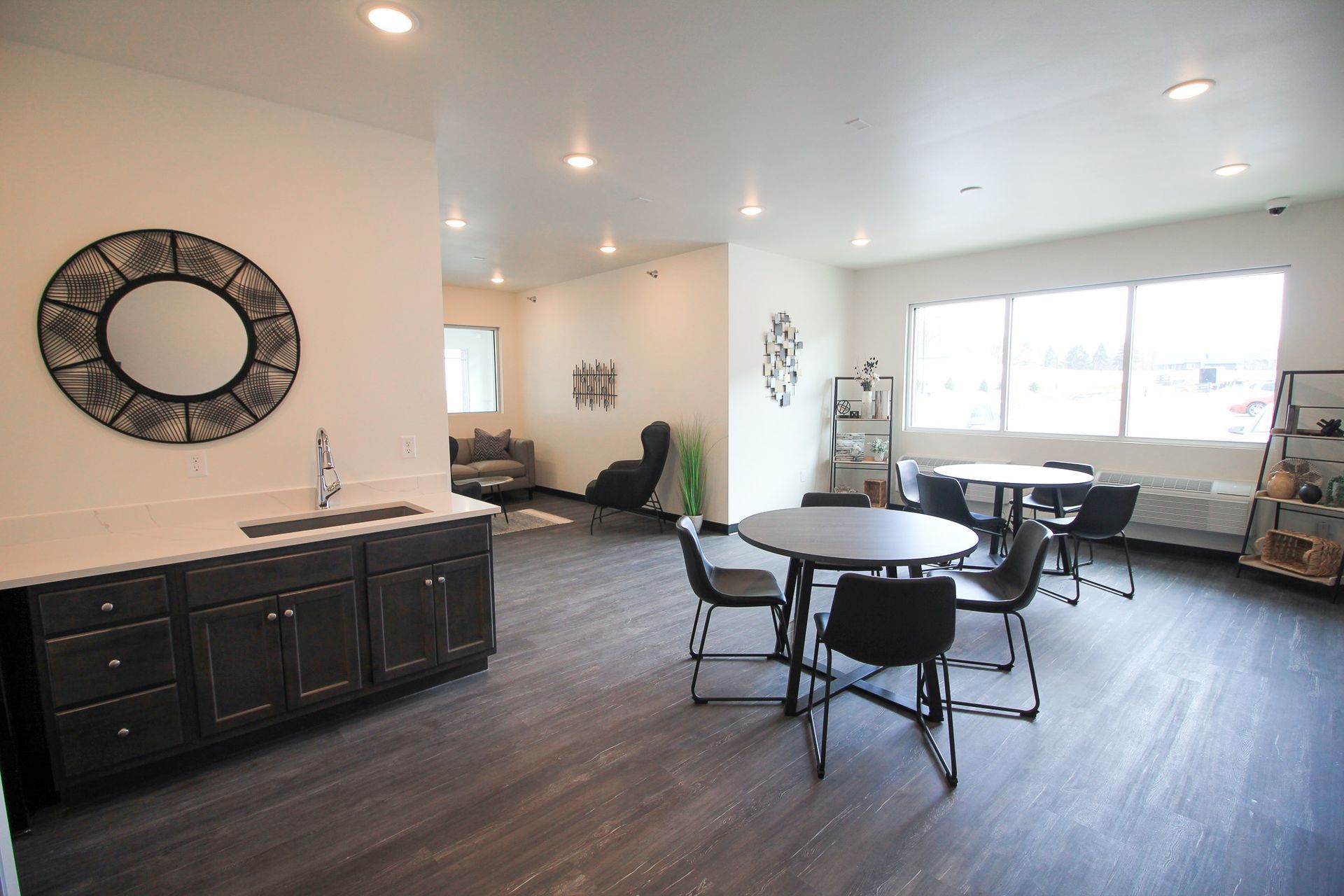 Modern open living room with round dining table, black cabinetry, and large bright windows