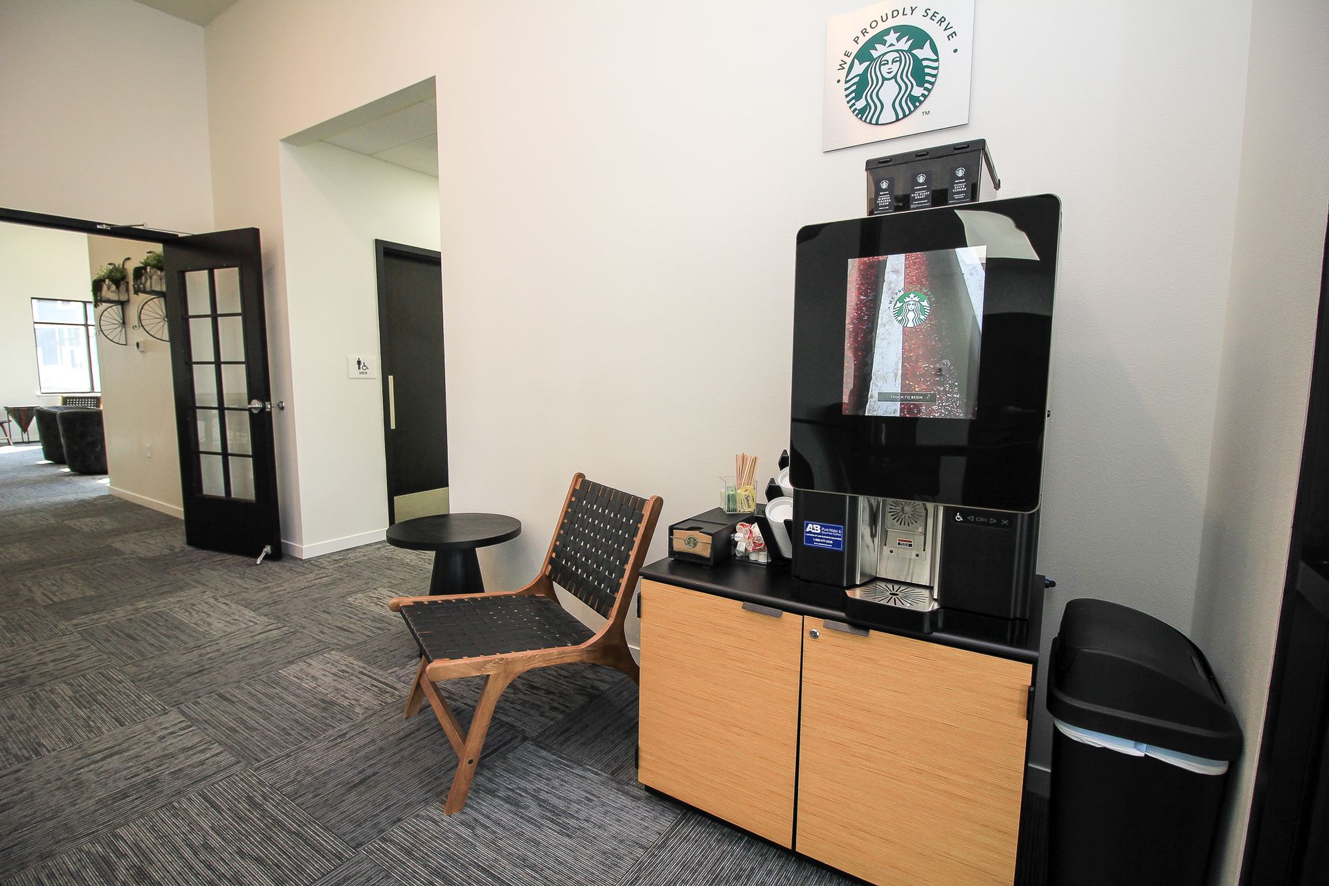 Lobby seating area with chair, side table, coffee station, and Starbucks sign