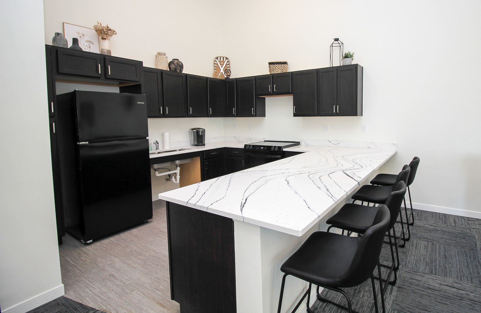 Modern black-and-white kitchen with island, bar stools, and black appliances