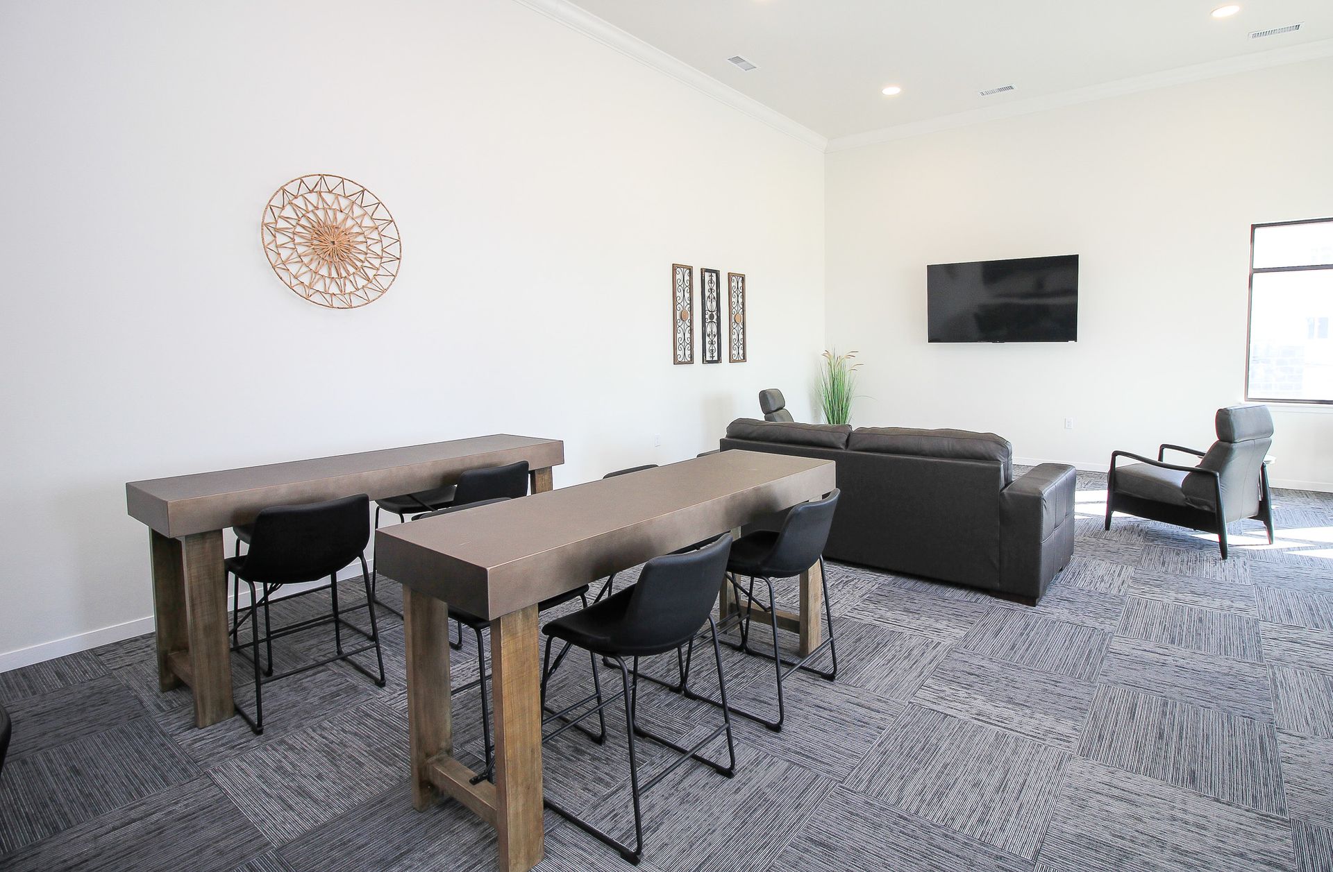 Modern living room with gray sofa, wall-mounted TV, bar table, and patterned rug under bright white walls