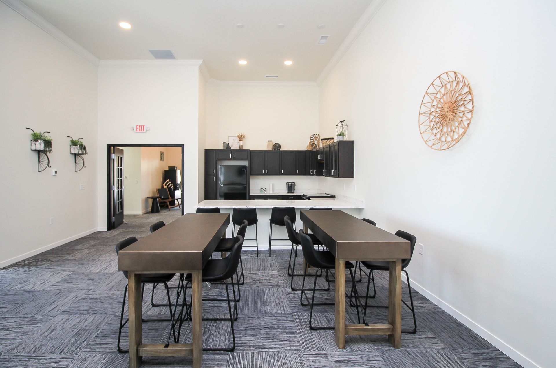 Modern kitchen and dining room with a long table, black chairs, white walls, and recessed lighting
