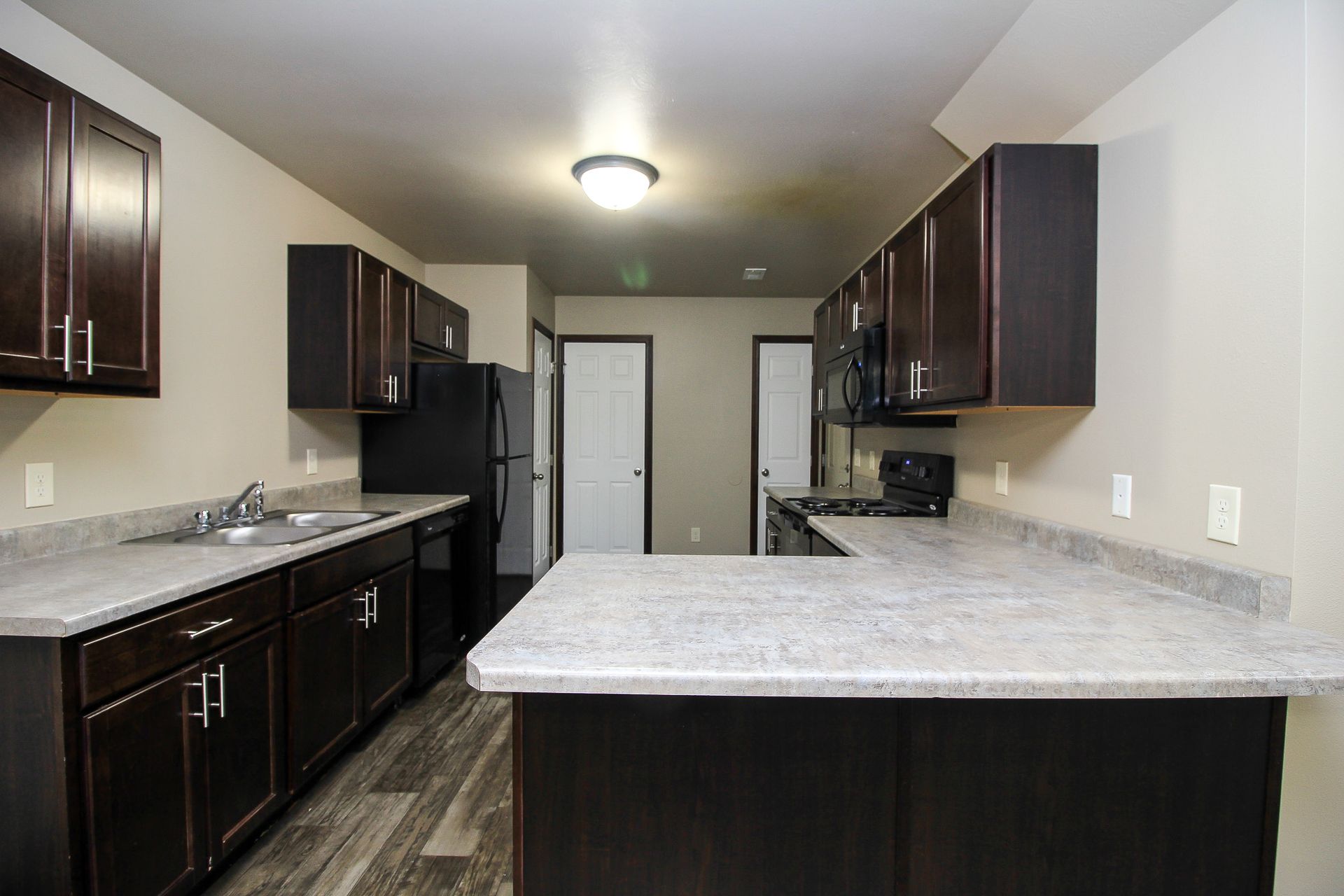 Modern kitchen with dark cabinets, black appliances, and a large gray island countertop