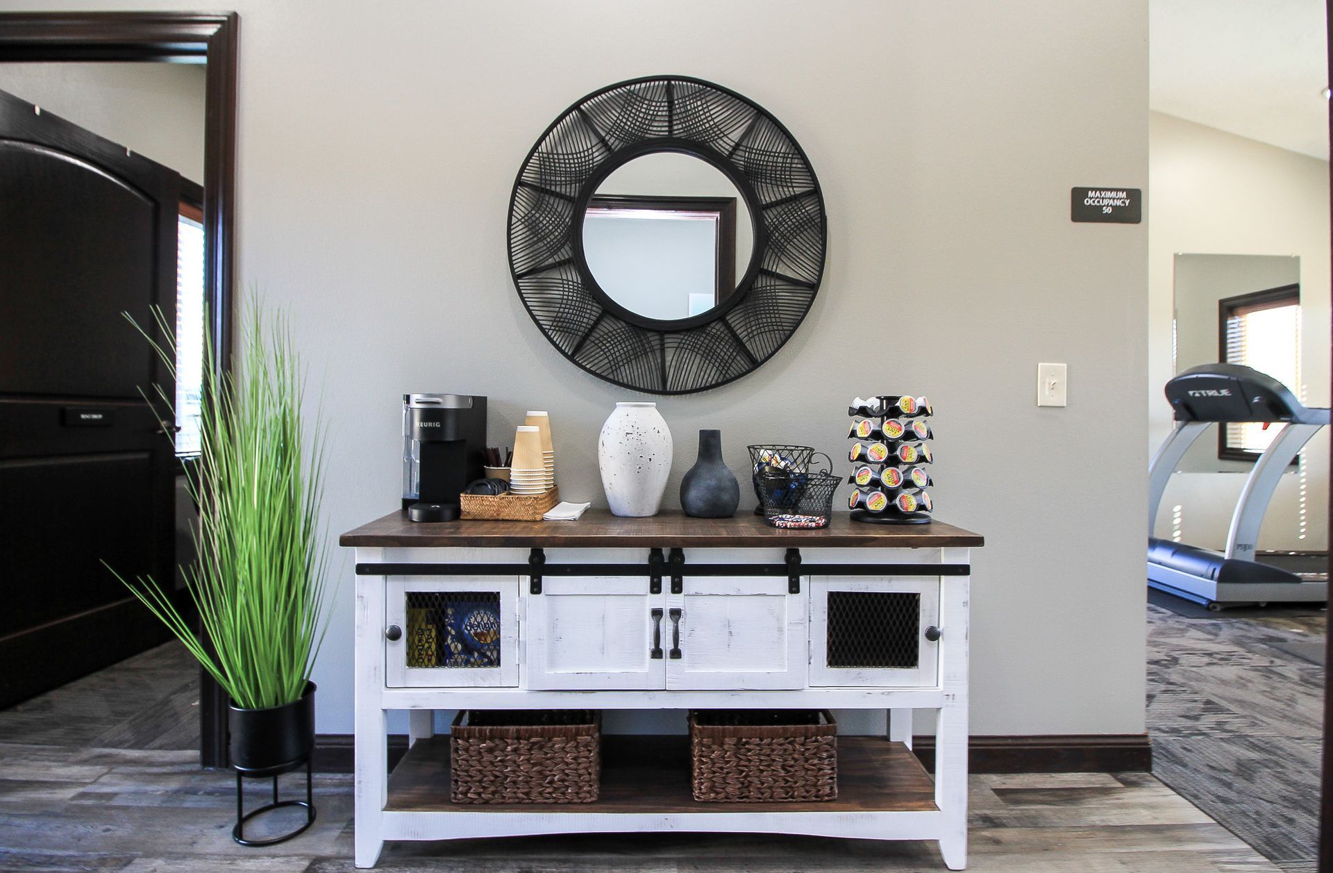 Entryway console table with mirror, decor, and a treadmill visible in an adjacent room.