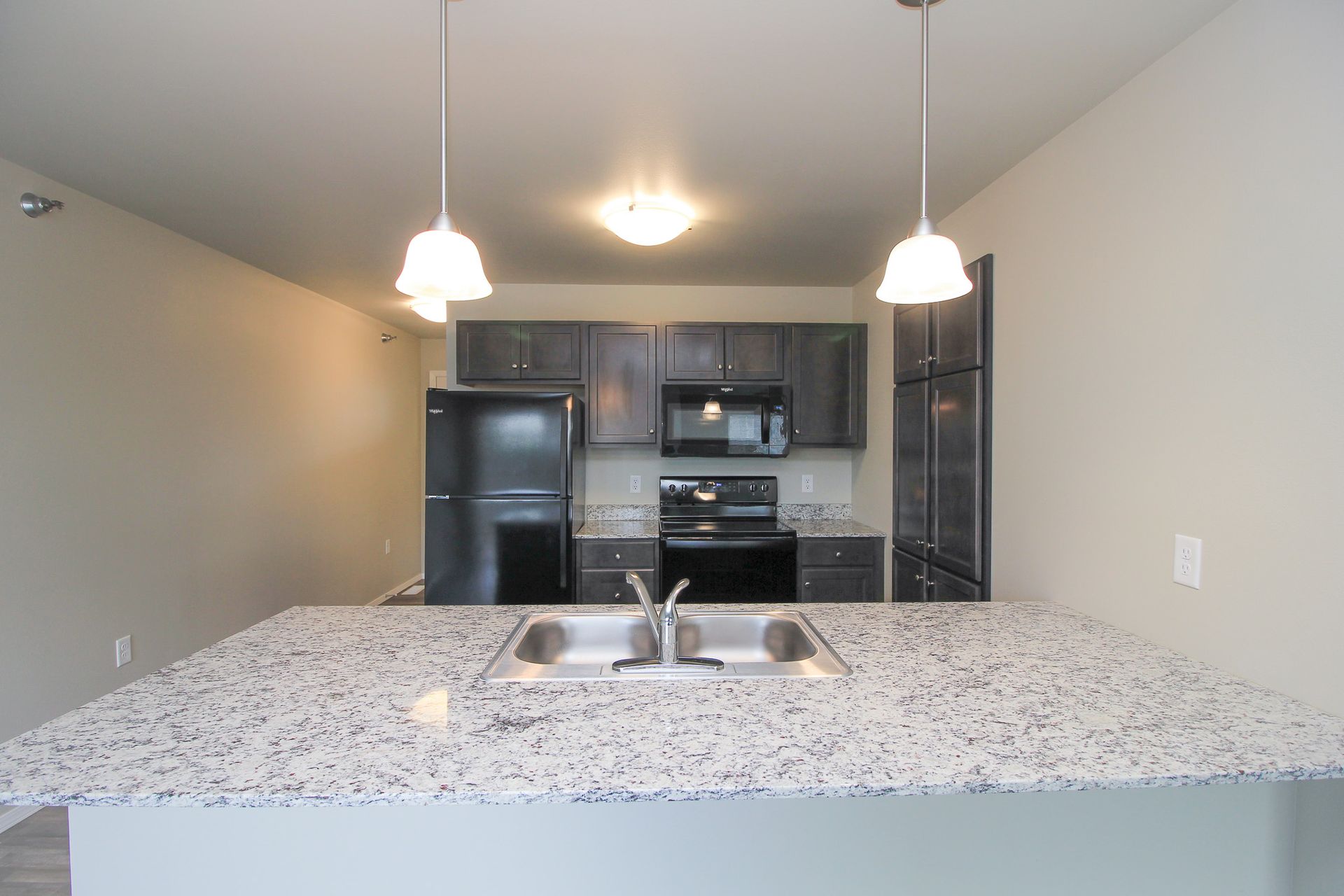 Modern kitchen with granite island, hanging pendant lights, and stainless steel appliances