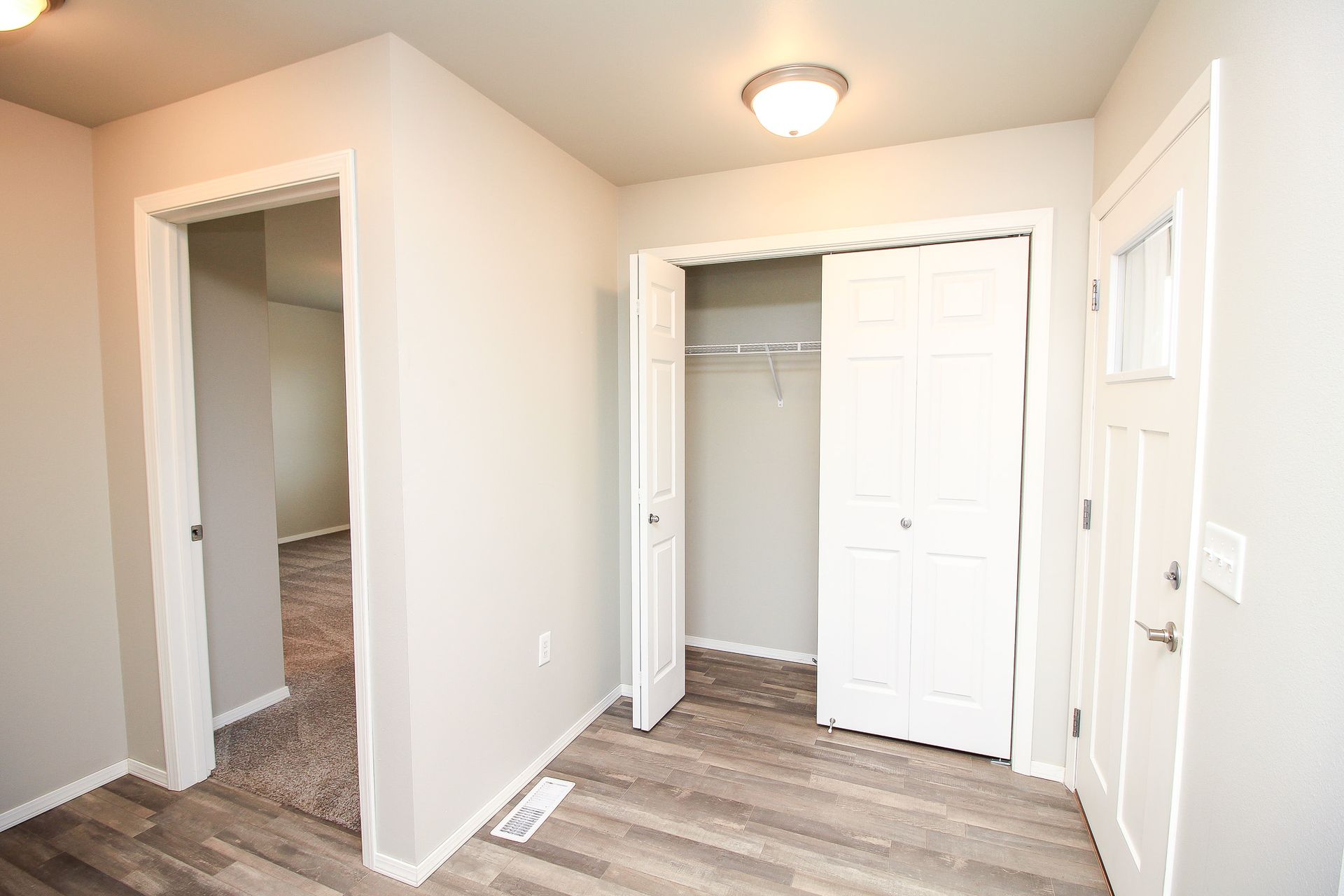 Empty hallway with two open closets, white walls, and gray wood flooring