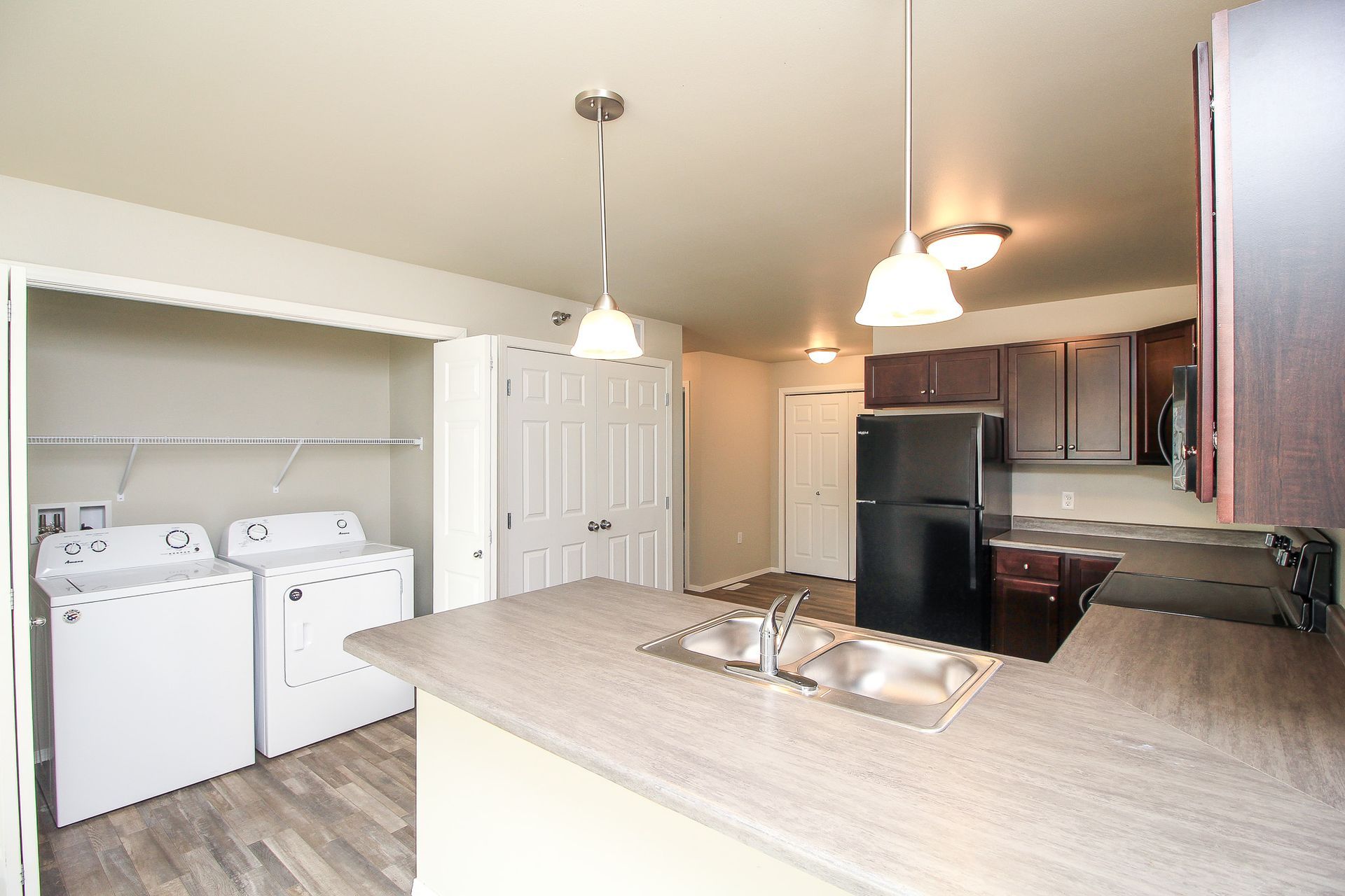 Kitchen with island and sink, black refrigerator, and laundry area with washer and dryer in the background