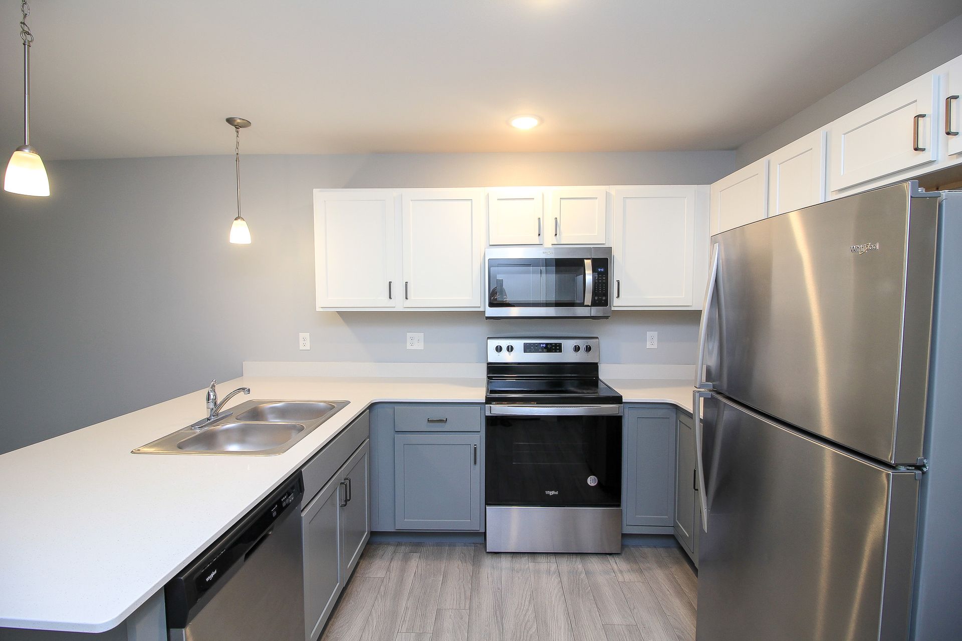 Modern kitchen with white cabinets, stainless steel appliances, island sink, and gray walls