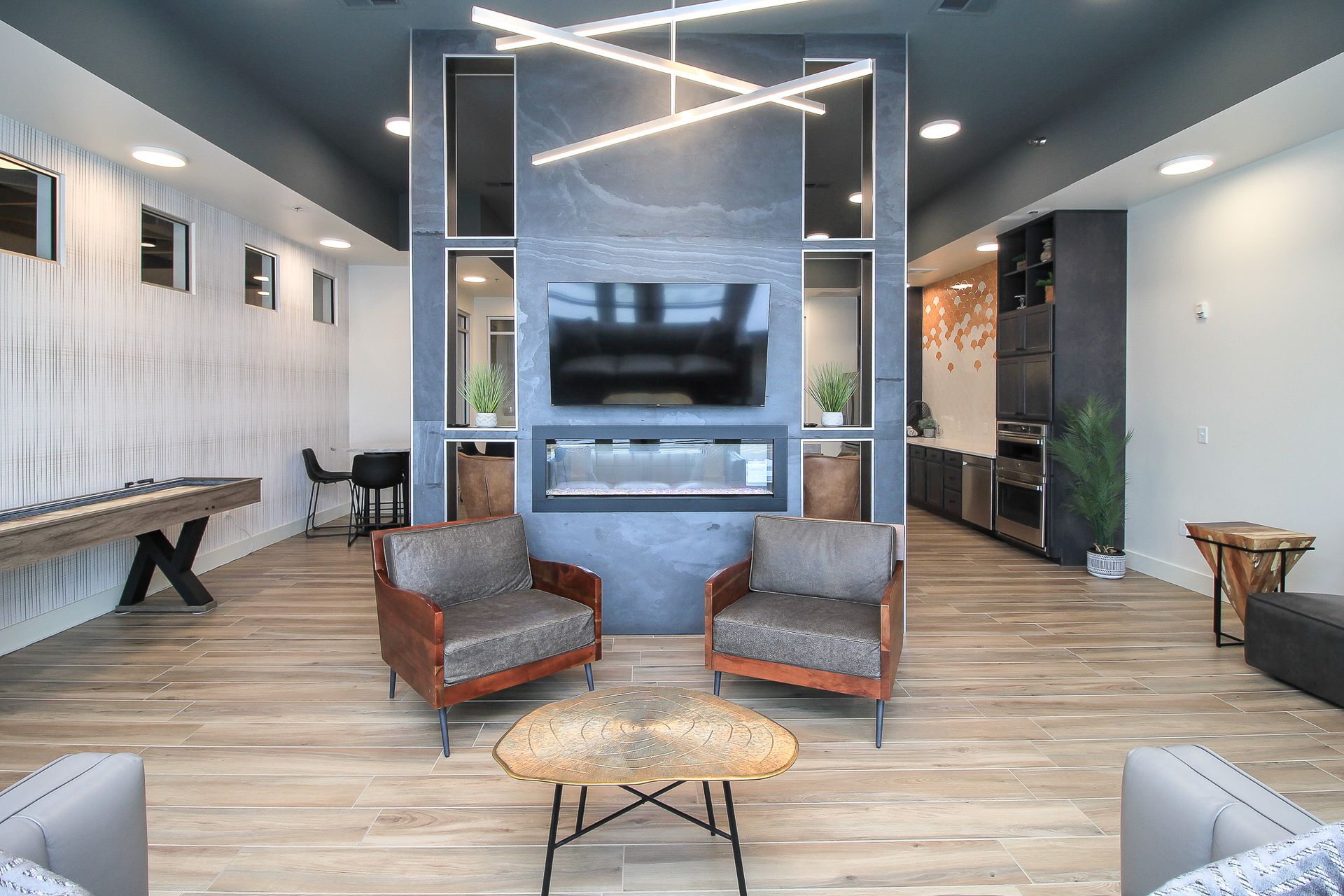Empty lounge with gray carpet, red beanbag seats, and neon wall art on a dark accent wall