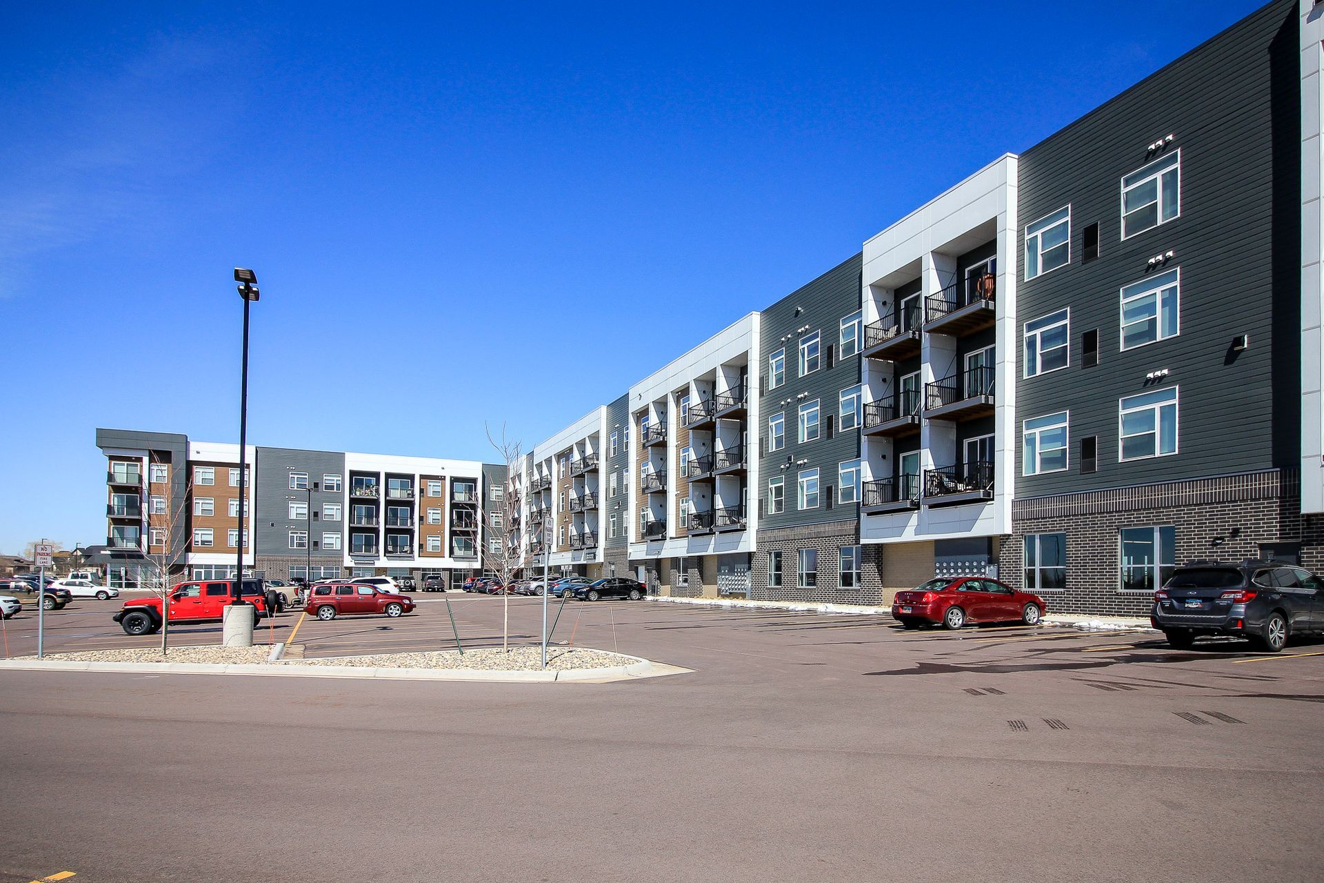 Modern multi-story apartment building with gray, white, and brown facade and balconies