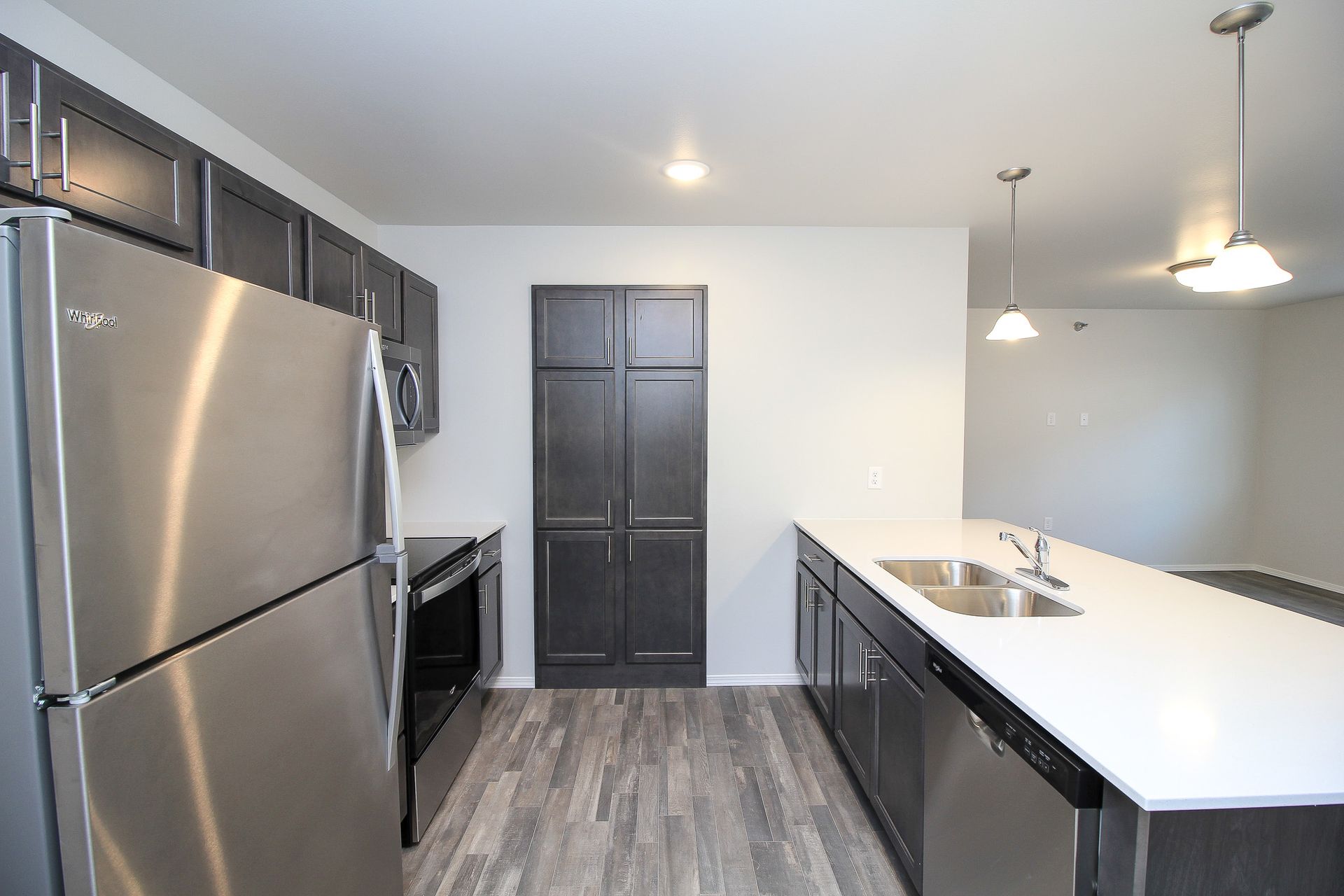 Modern kitchen with stainless steel appliances, dark cabinets, and a white island countertop
