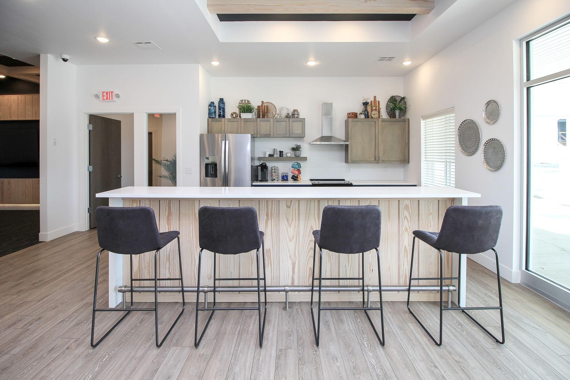 Modern kitchen with white island and four dark bar stools in a bright open space