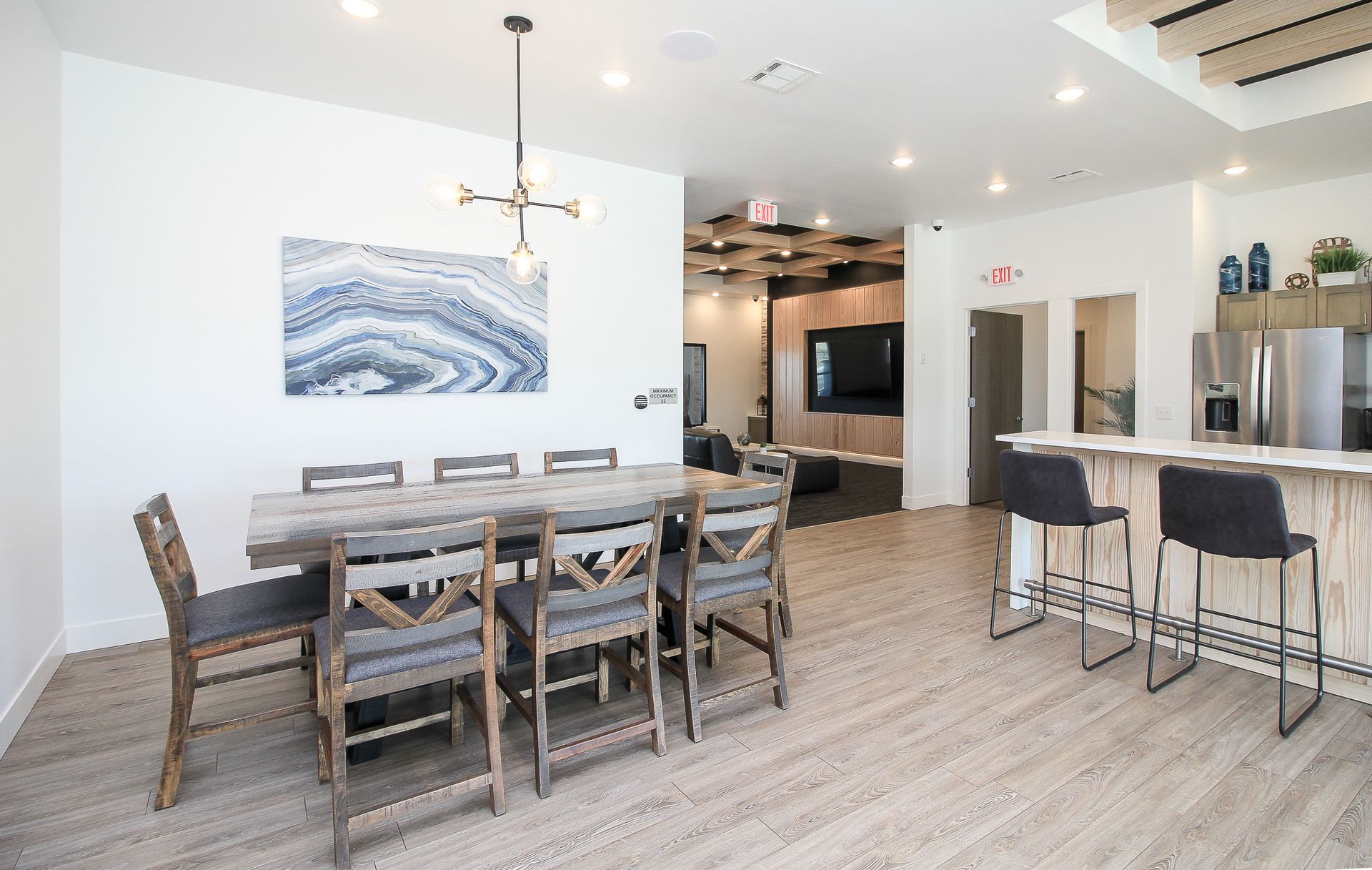 Modern dining area with long table, bar stools, and kitchen island in a bright open space