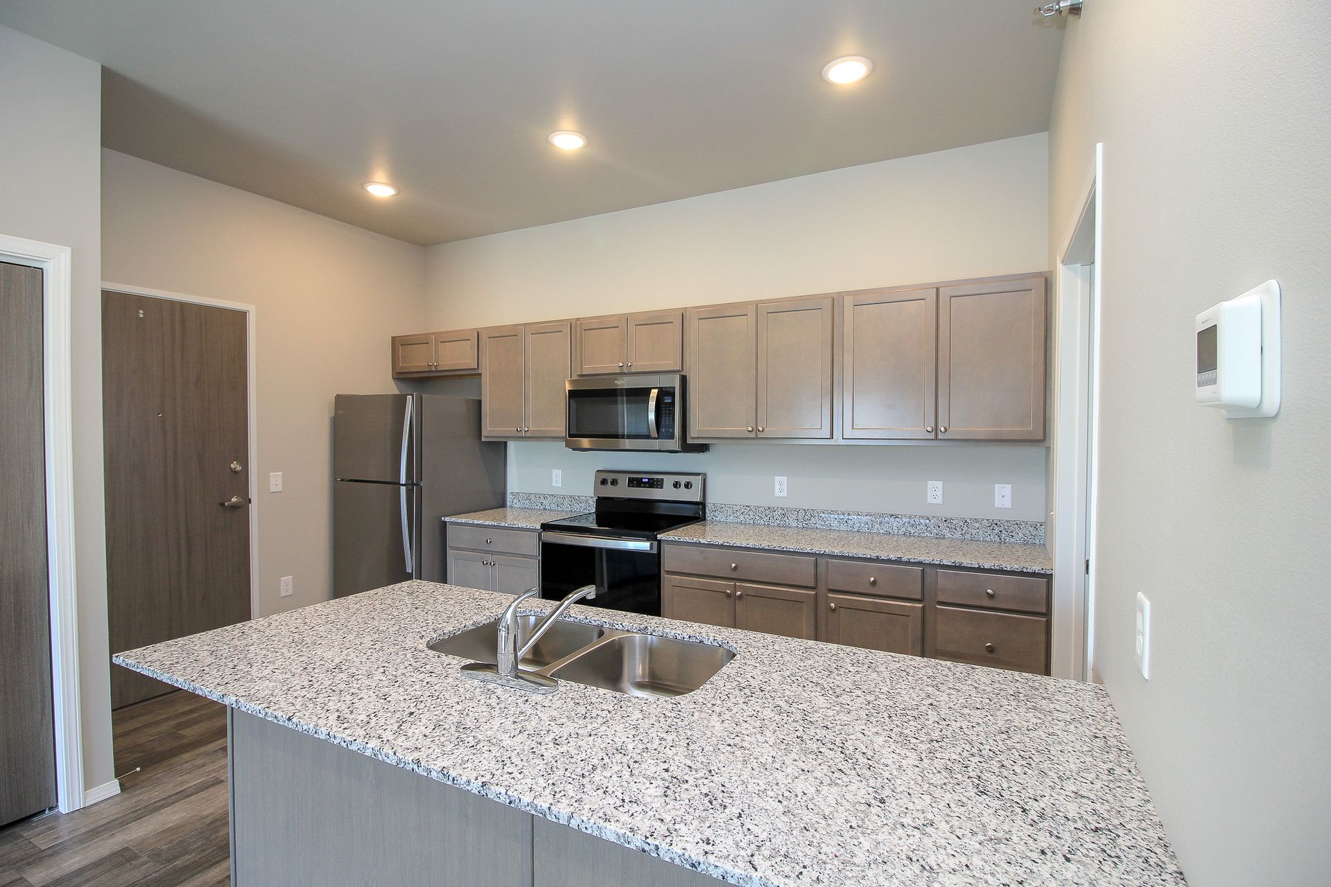 Modern kitchen with granite island, stainless steel appliances, and light wood cabinets