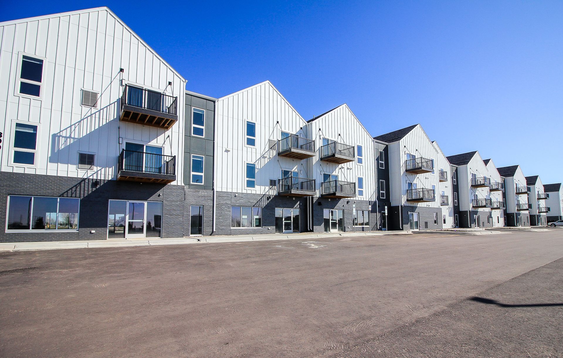 Modern white apartment buildings with balconies under a clear blue sky