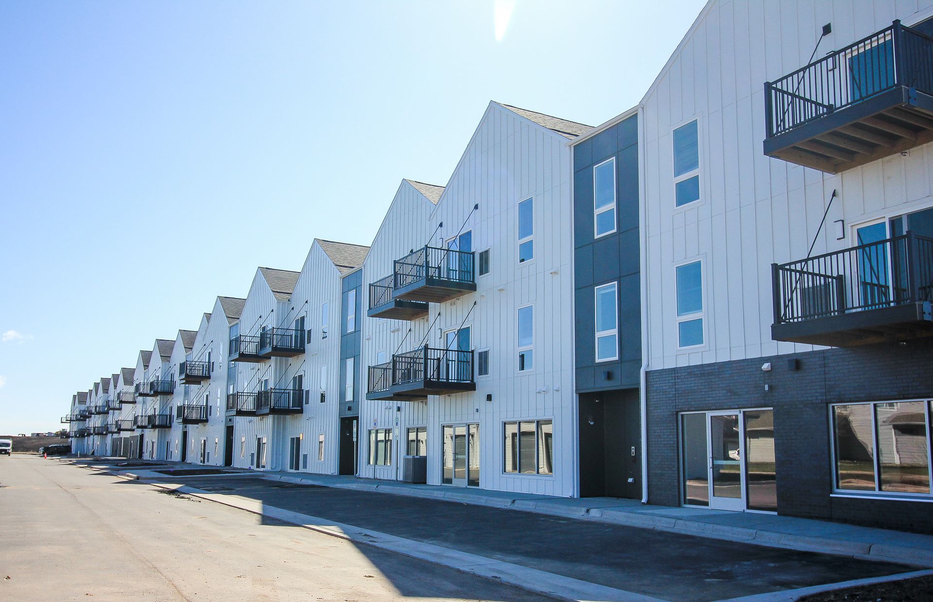 Row of modern apartment buildings with balconies along a sunny street