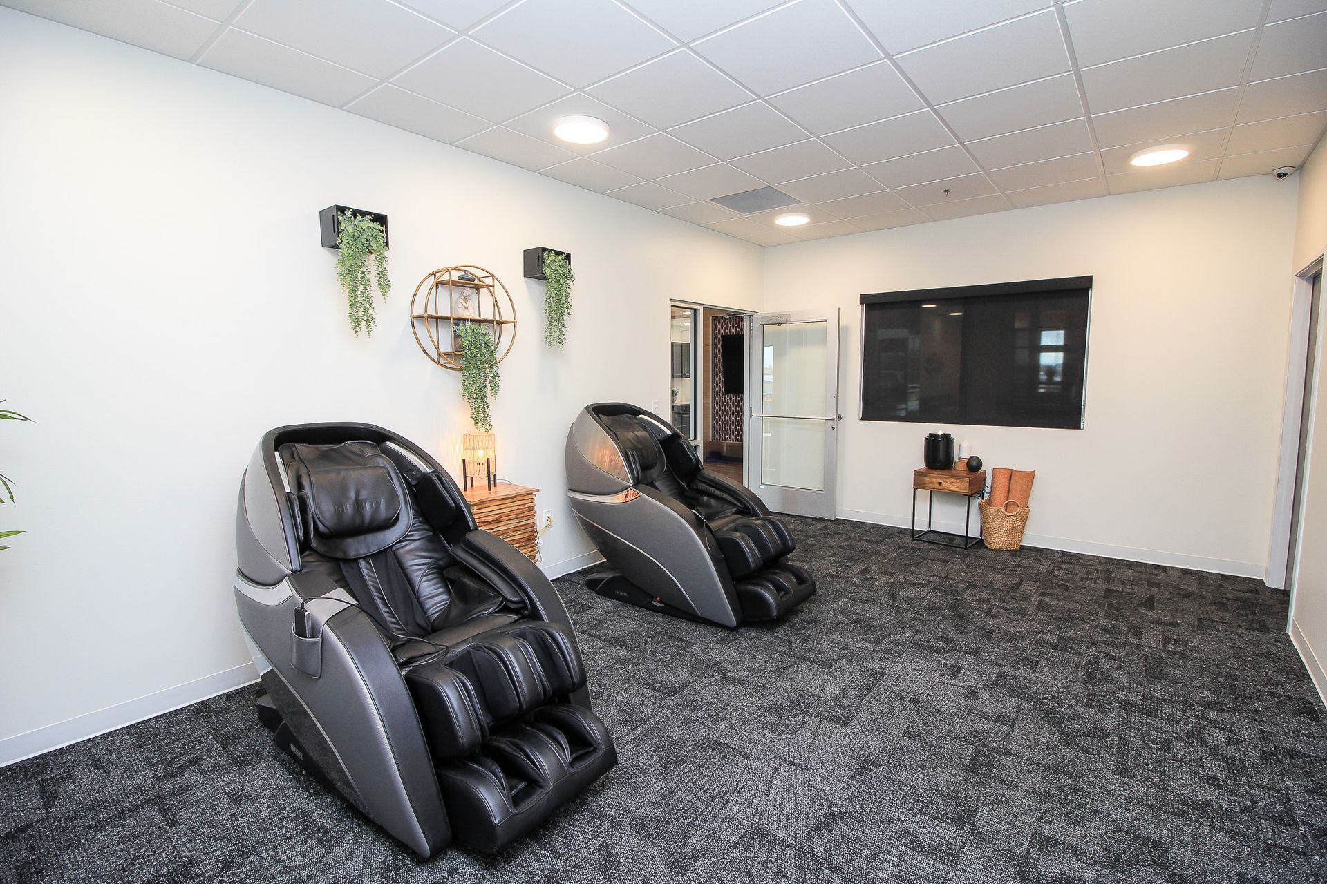 Bright gym room with mirrored wall, black equipment racks, and red patterned carpet.