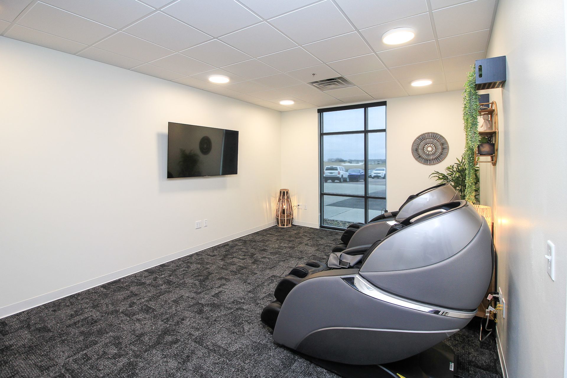 Modern living room with two brown chairs, black sofa, round coffee table, and wall-mounted TV fireplace