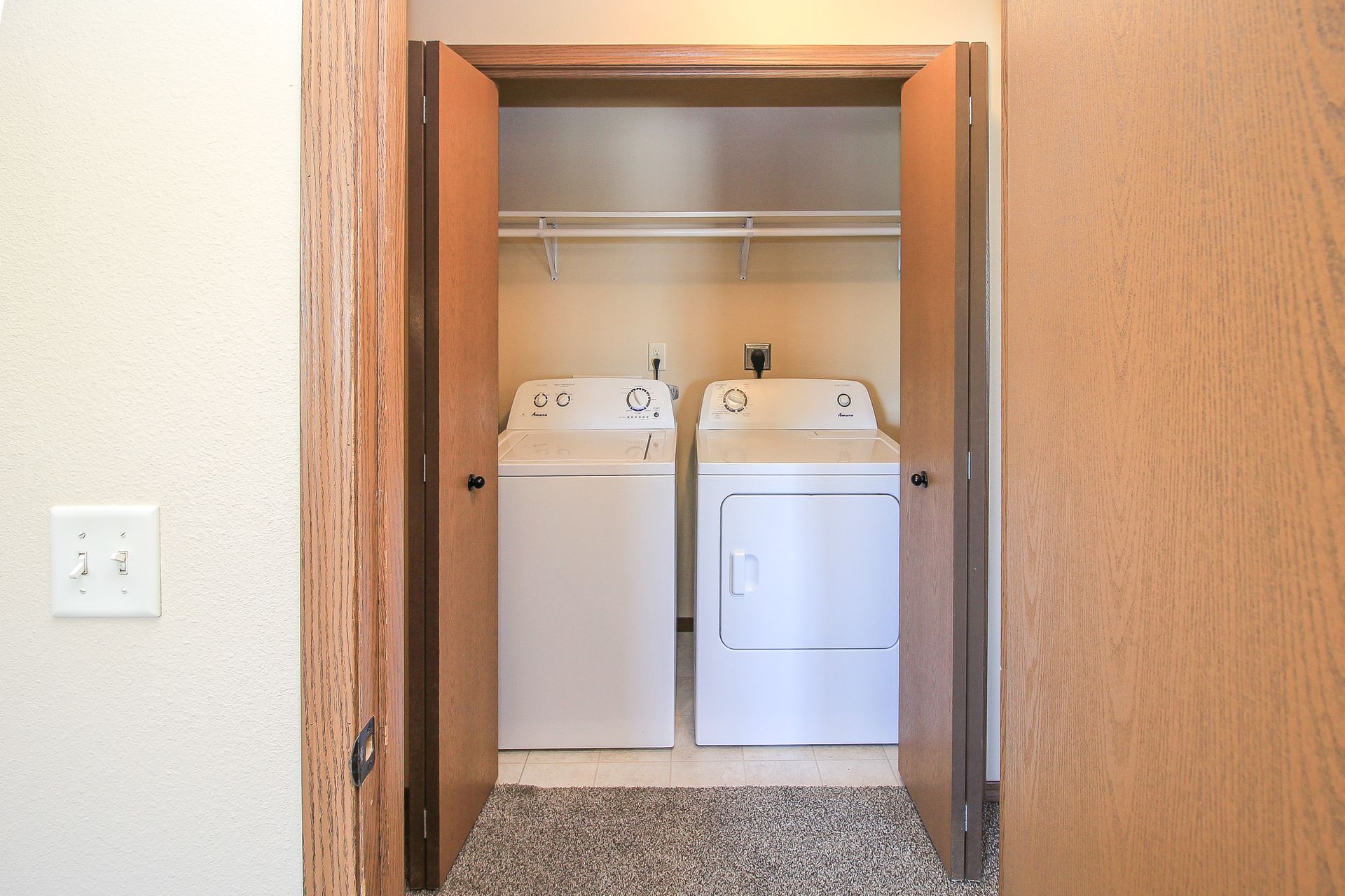 Laundry nook with a washer and dryer behind an open wooden door