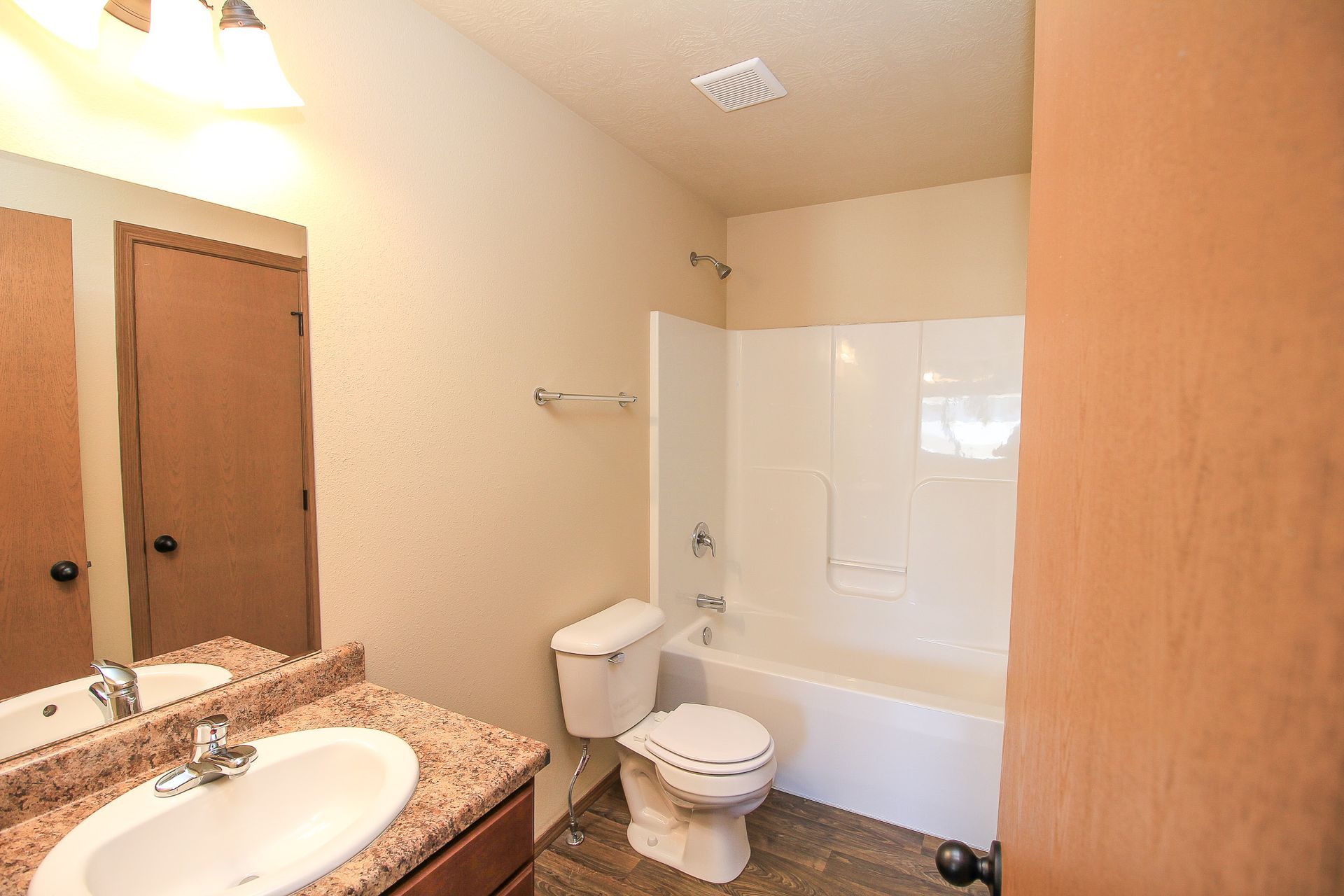 Small bathroom with sink, toilet, bathtub, beige walls, and wood cabinets
