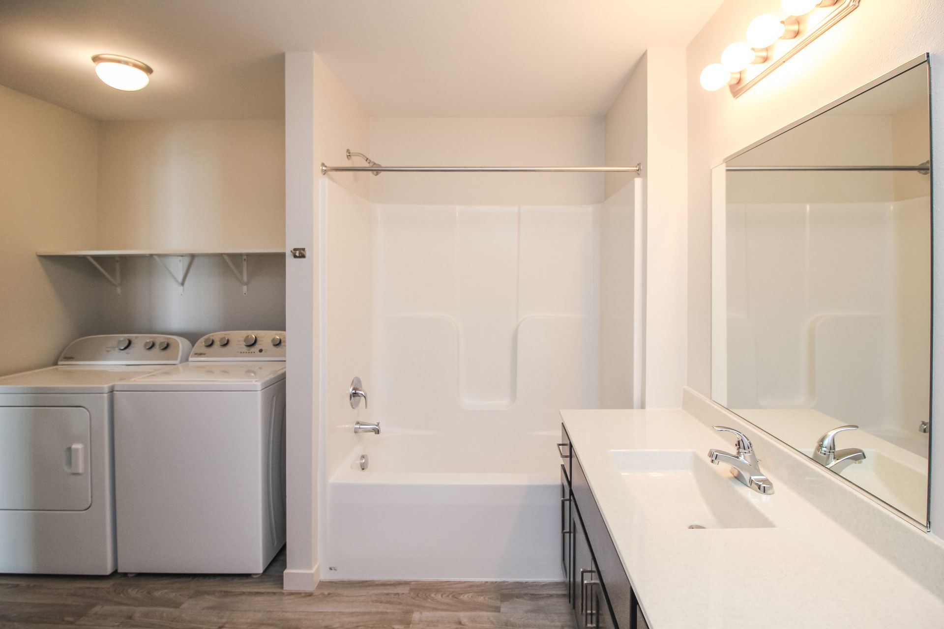 Laundry room and bathroom combo with washer, dryer, vanity, mirror, and tub-shower.