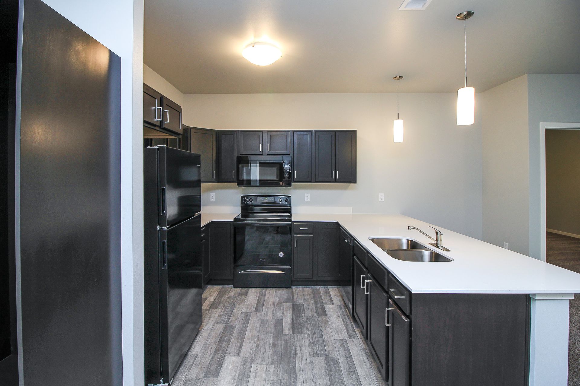 Modern kitchen with dark cabinets, black appliances, white island, and gray flooring