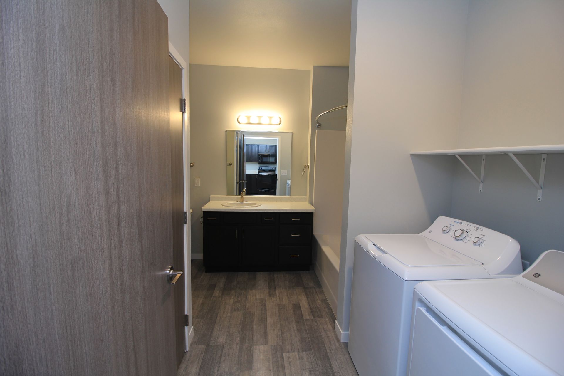 Laundry room with washer, dryer, sink vanity, and mirror in a narrow hallway