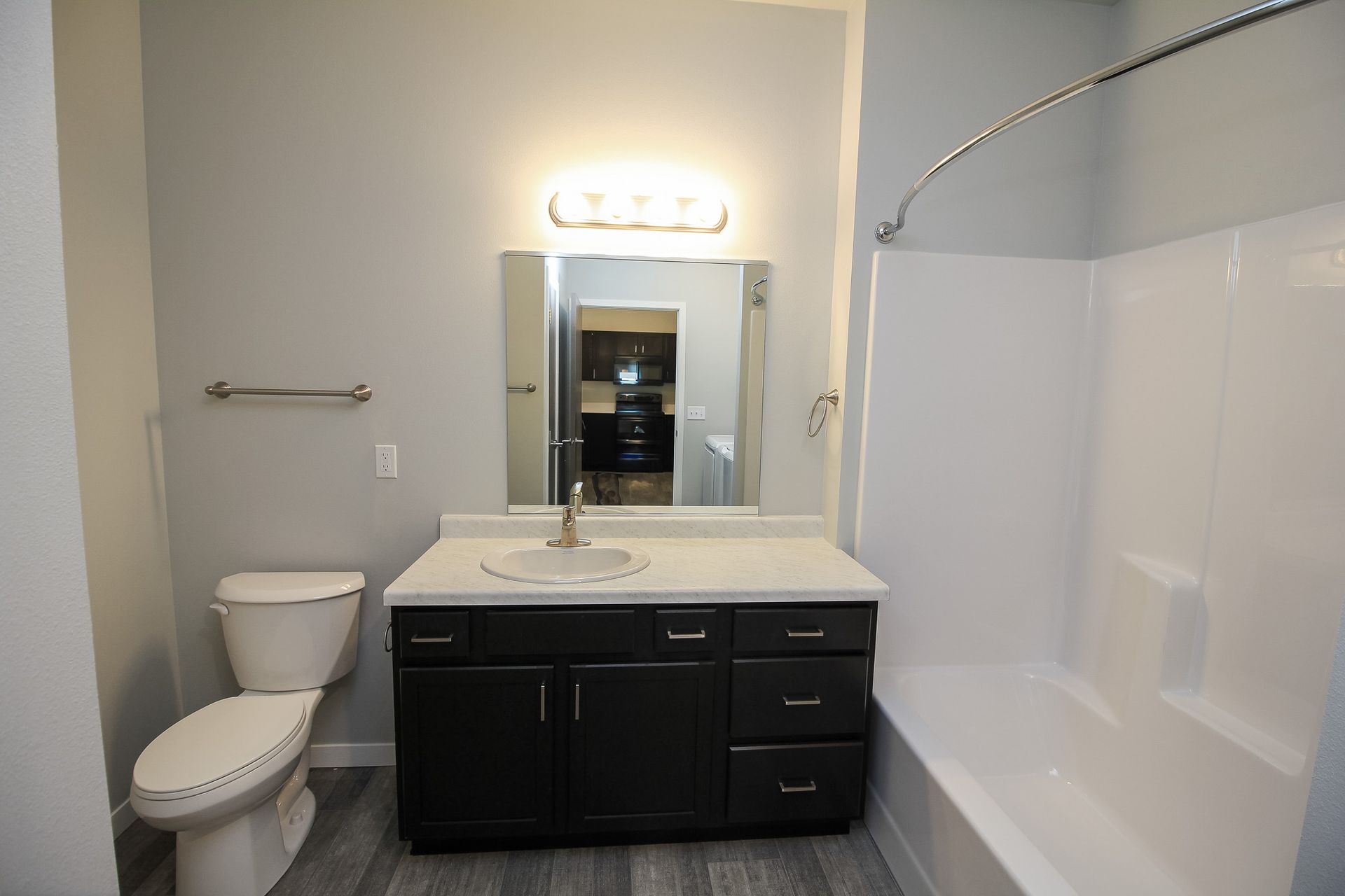 Bathroom with toilet, vanity sink, mirror, and bathtub with white surround