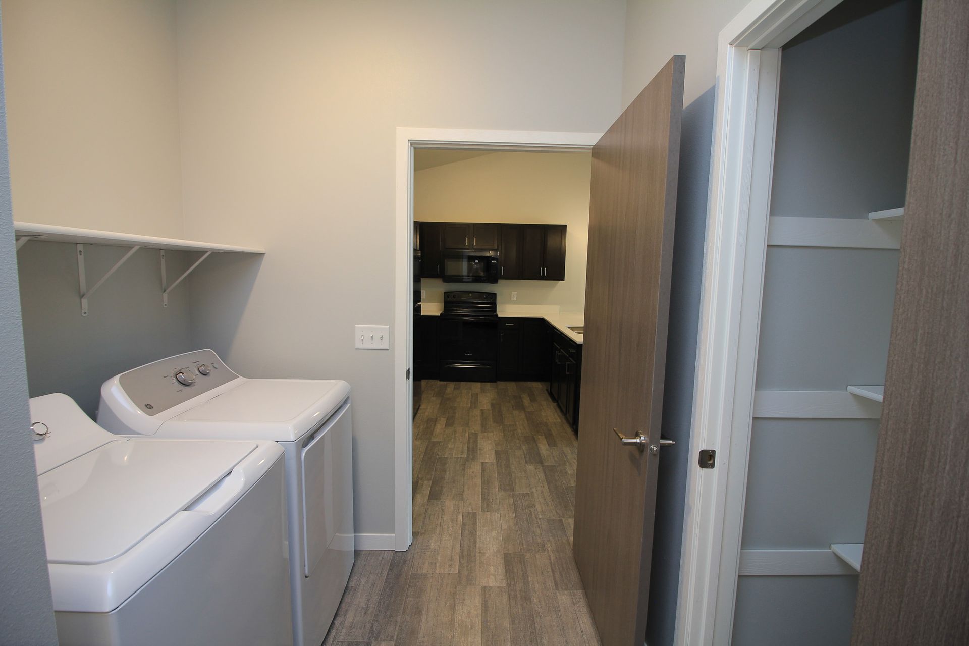 Laundry room with washer and dryer, open closet, and a doorway to a kitchen area
