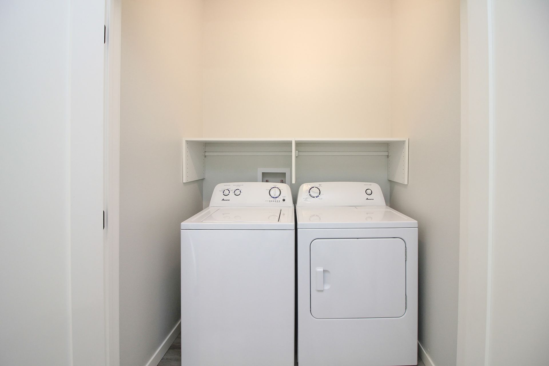Laundry area with a white top-load washer and front-load dryer in a narrow closet.