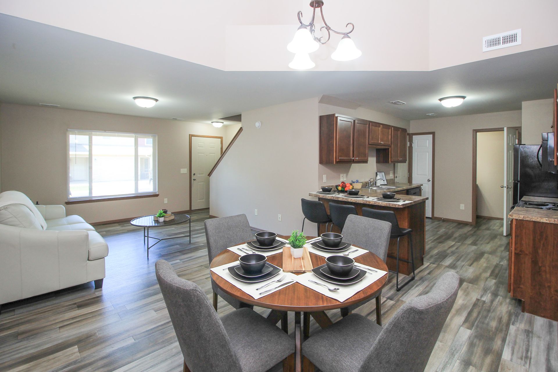Open-plan living room and kitchen with white sofa, dining table, and wood cabinetry