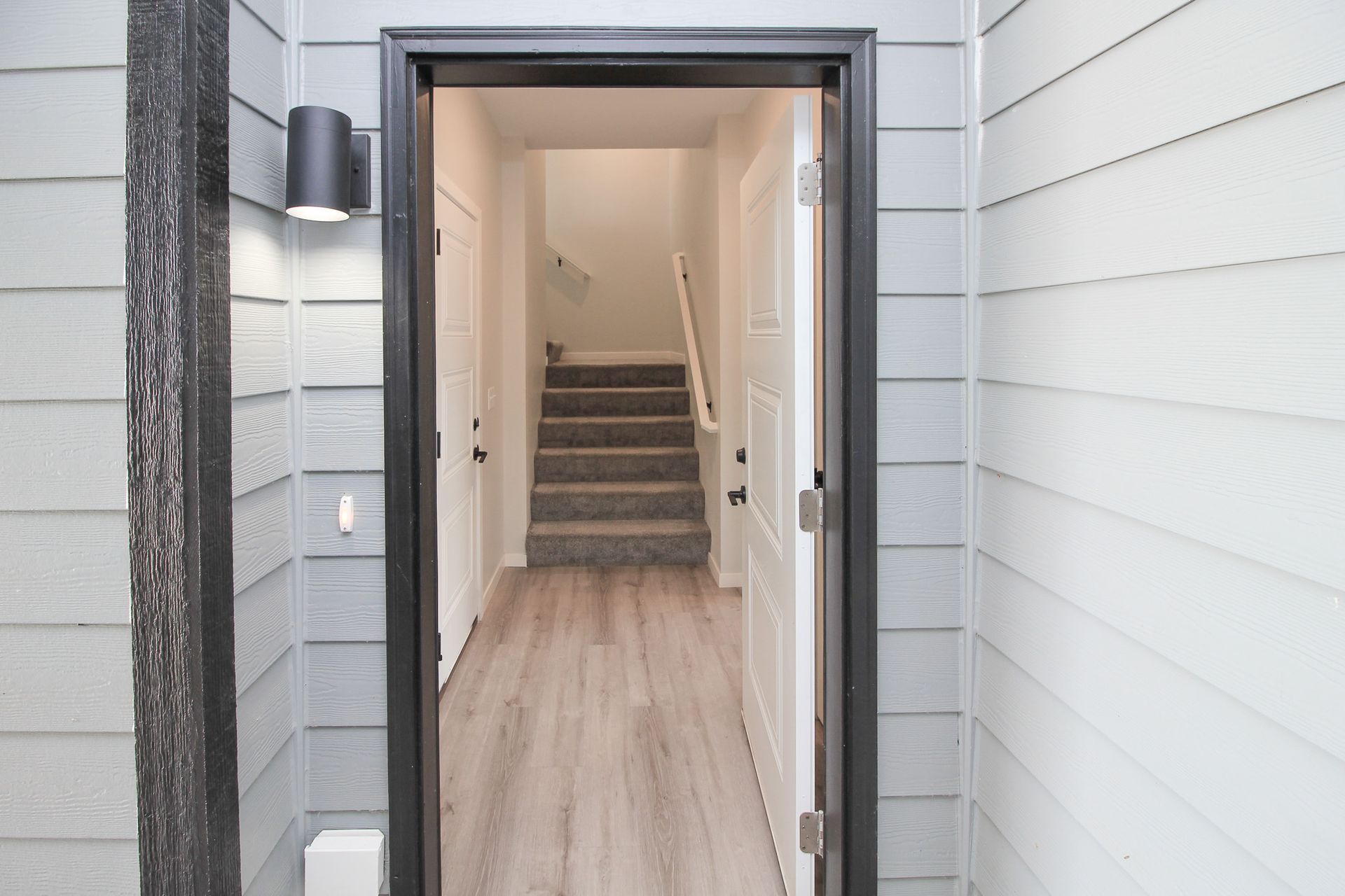 Open front door showing a white entry hallway with stairs leading up inside