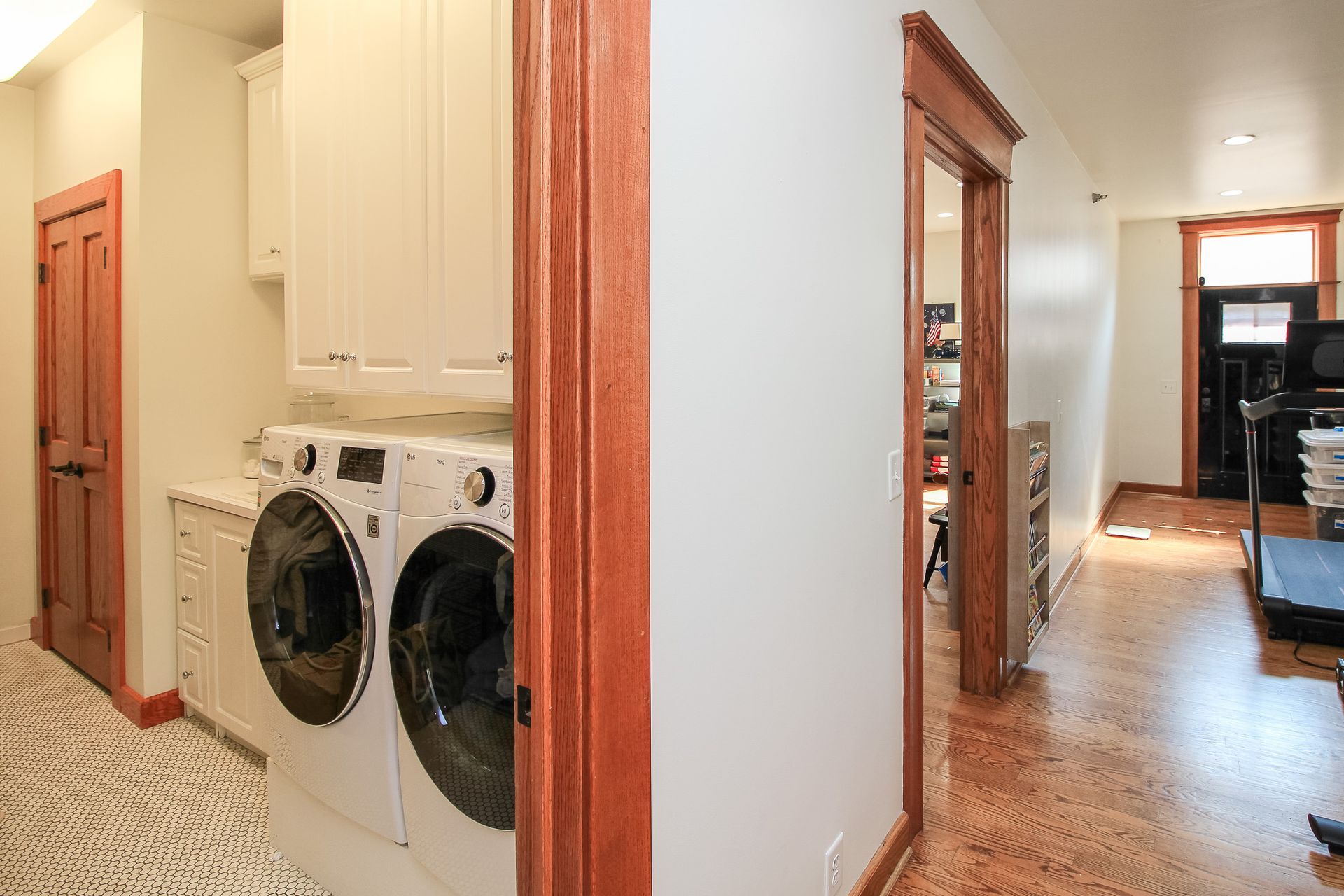 Laundry area with stacked washer and dryer beside a hallway leading to a kitchen.