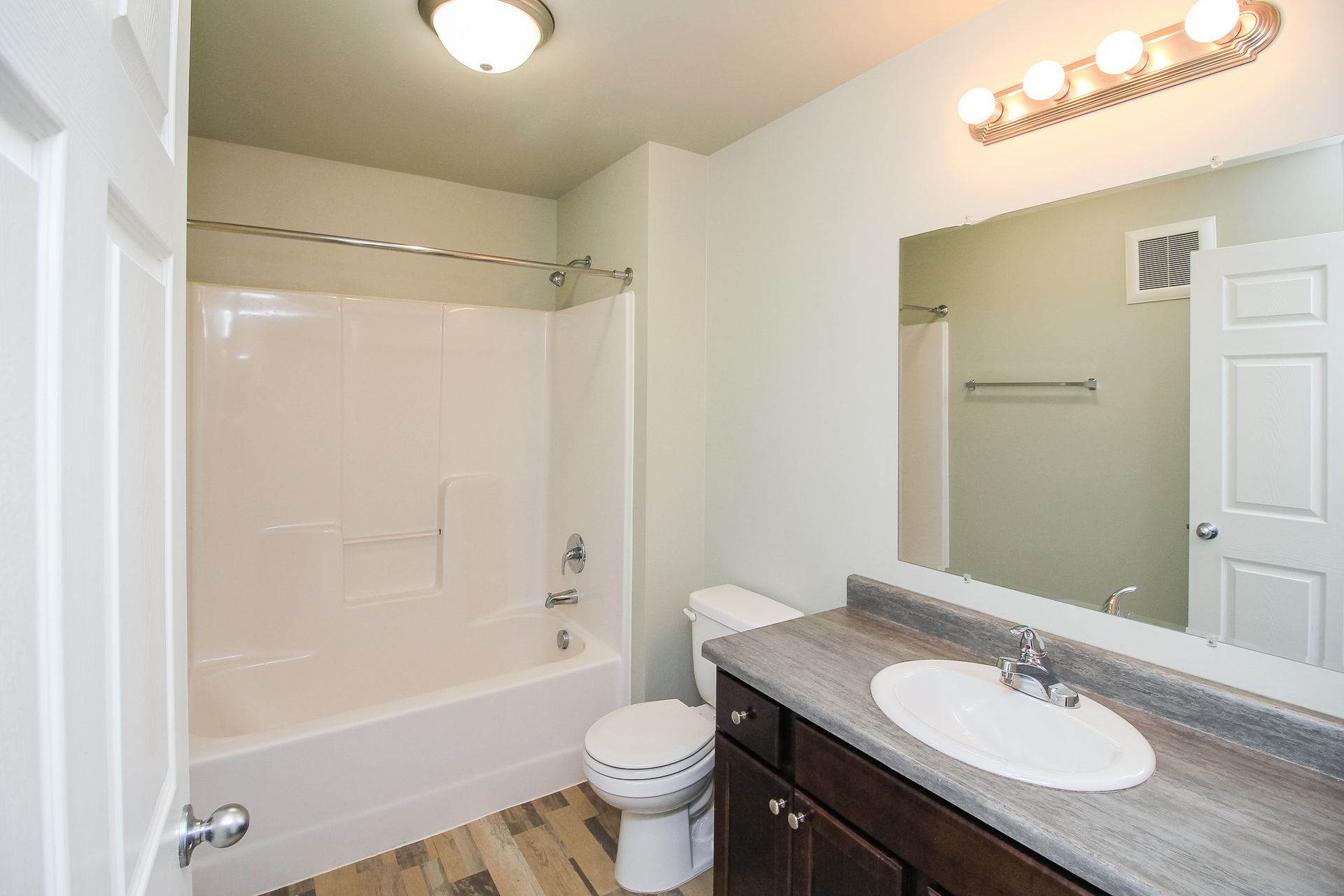 Small bathroom with shower-tub, toilet, and vanity sink under bright lights.