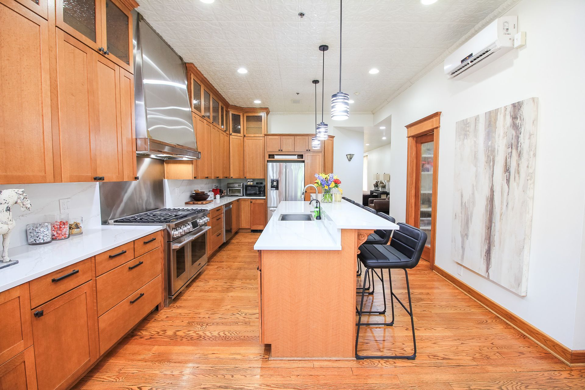 Bright kitchen with wooden cabinets, stainless appliances, and a white island with bar stools.