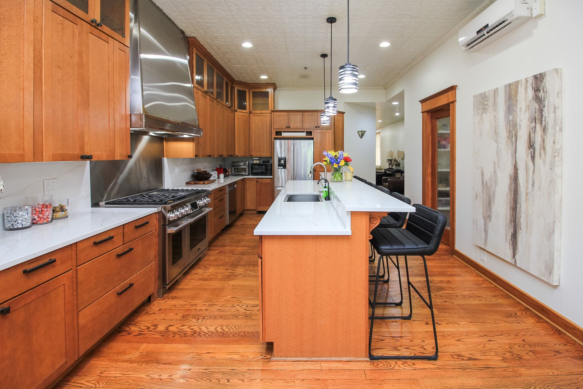 Modern kitchen with wood cabinets, stainless appliances, and a large island under pendant lights