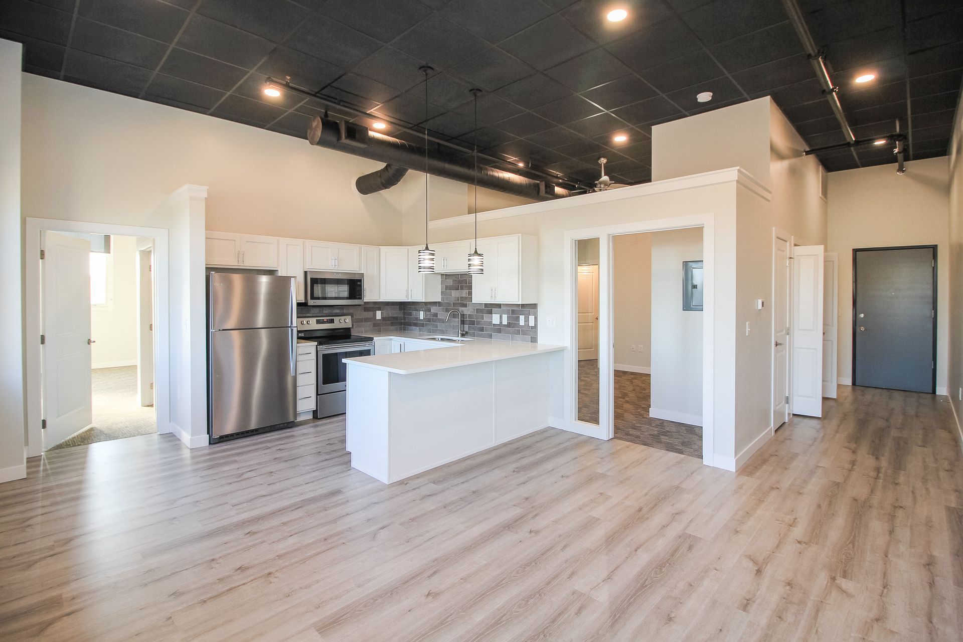 Open-concept apartment with kitchen island, stainless steel fridge, and light wood floors