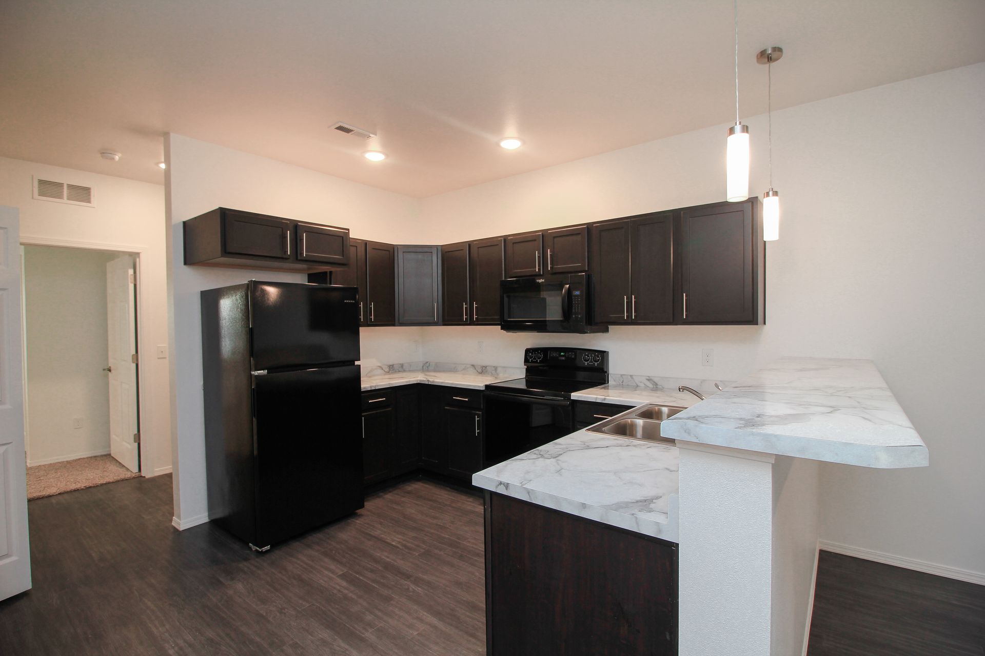 Modern kitchen with dark cabinets, black appliances, and white marble countertops