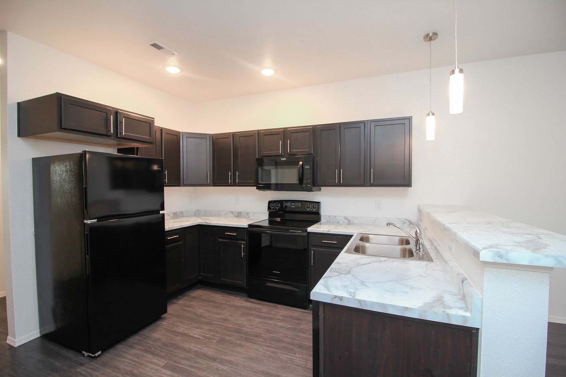 Modern kitchen with black cabinets, black appliances, and a white marble-style countertop.