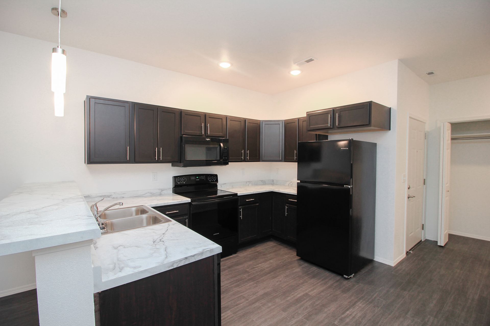 Modern kitchen with dark cabinets, black appliances, and white countertops