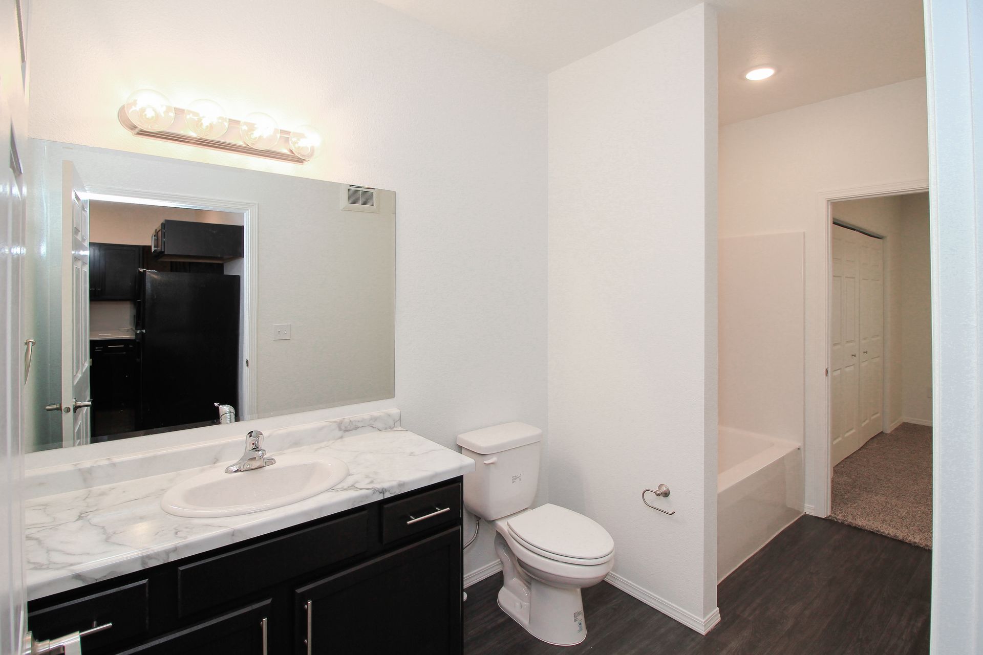 Small beige hallway closet with open white door and hanging shelf inside