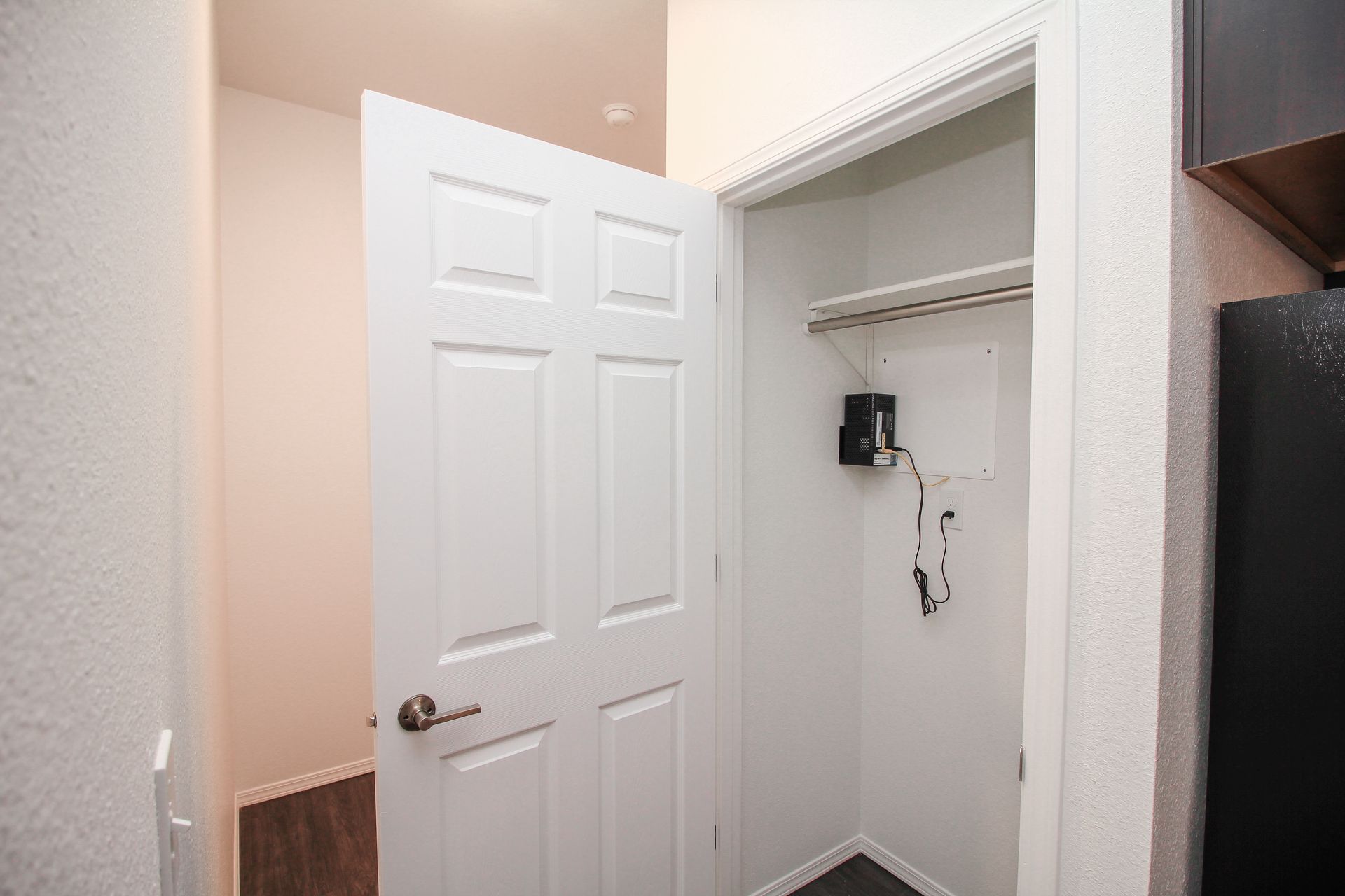 Empty bedroom with white walls, carpet, closet doors, and an open door to a hallway.