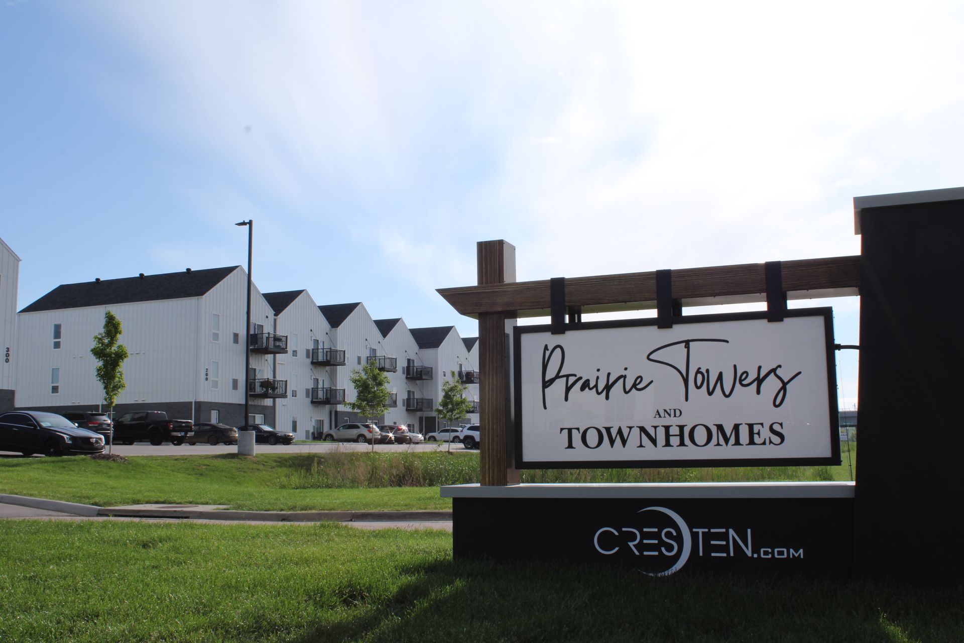 Prairie Views Townhomes sign in front of white apartment buildings under a blue sky